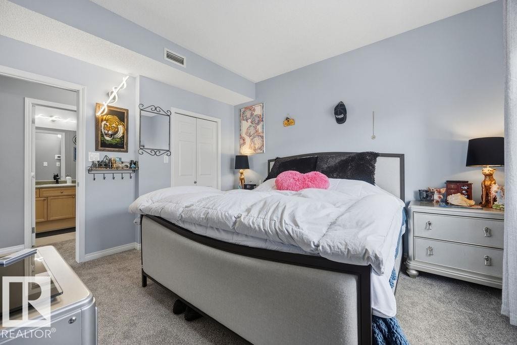 Carpeted bedroom featuring a double-door closet, access to a bathroom, and light blue walls - 71 3040 Spence Wynd, Edmonton, AB