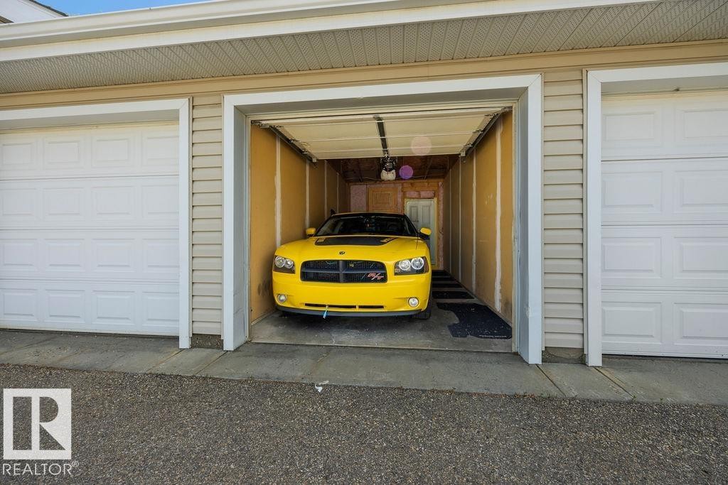 Multi-bay garage exterior featuring white paneled doors and tan horizontal siding - 71 3040 Spence Wynd, Edmonton, AB