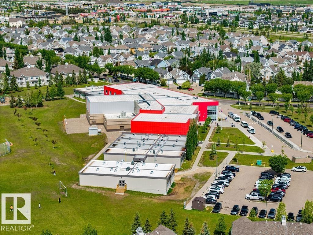 Spacious campus featuring multiple buildings with red and white facades, extensive parking facilities, and surrounding green spaces - 71 3040 Spence Wynd, Edmonton, AB