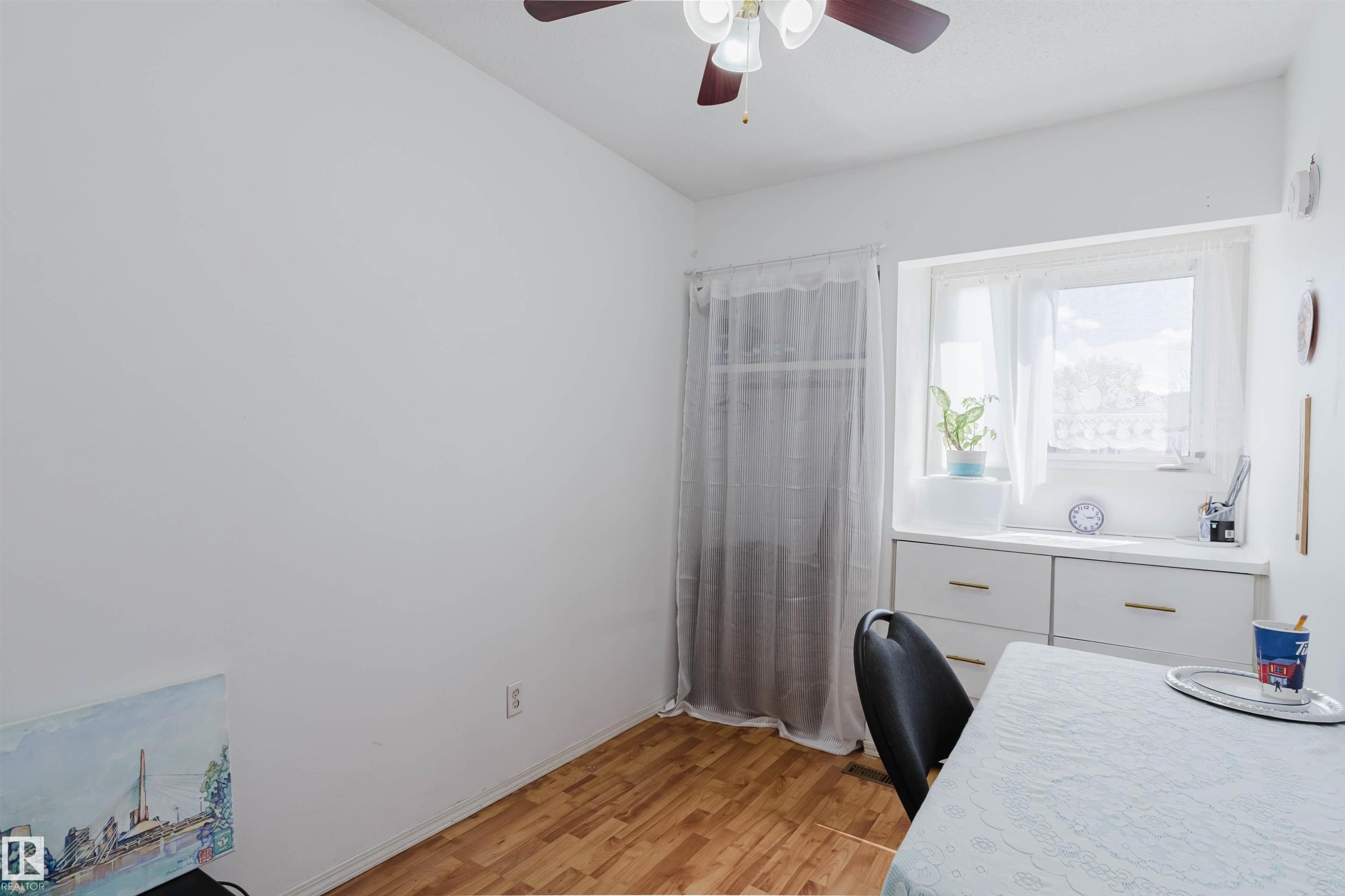 Room featuring wood-finish flooring and a ceiling fan with integrated lighting - 4 14310 80 Street, Edmonton, AB
