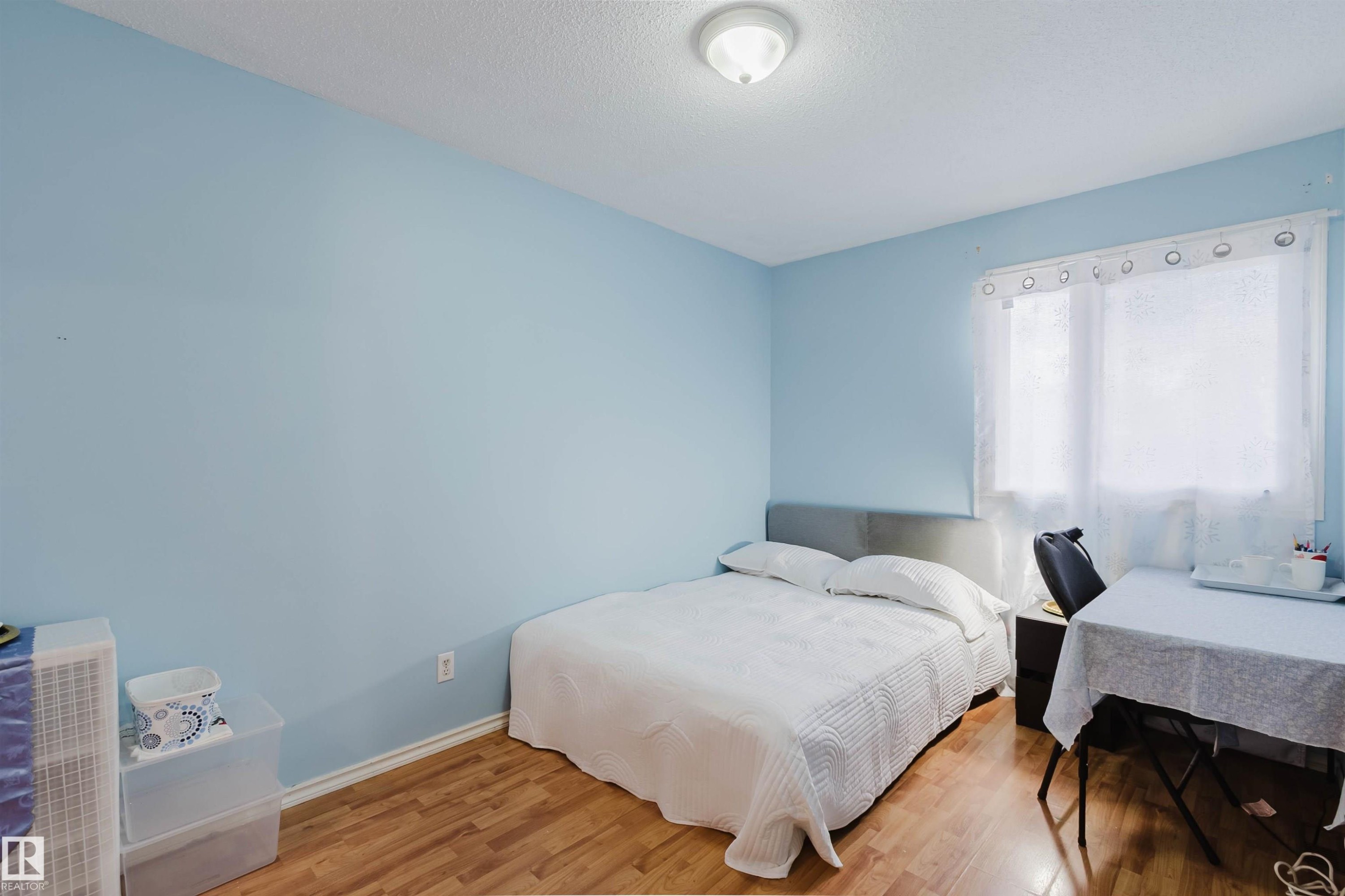 Bright room with a window, light blue walls, and wood-finish flooring - 4 14310 80 Street, Edmonton, AB
