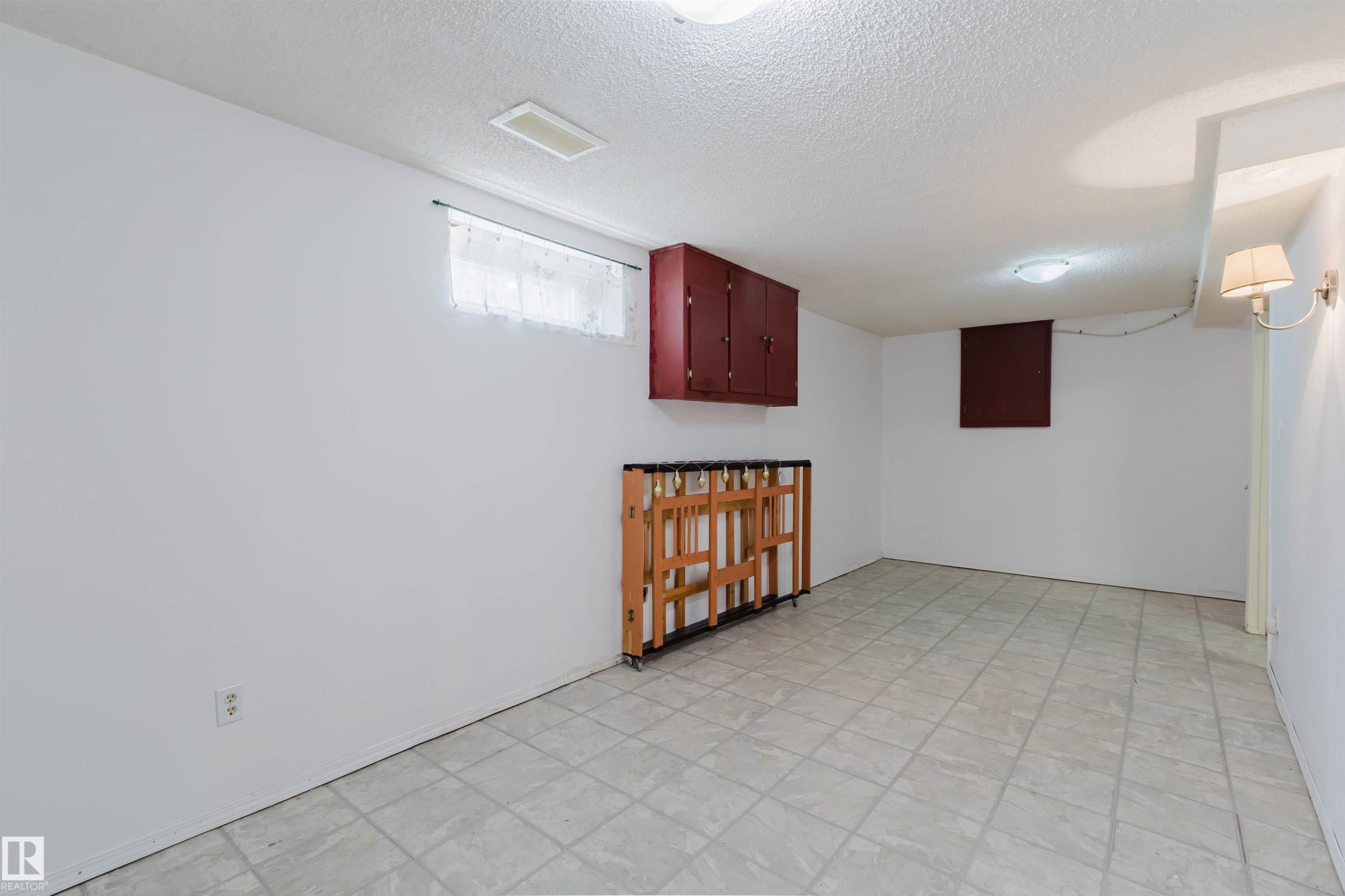 Spacious room with light-toned floor tiles, white painted walls, and ceiling-mounted light fixtures - 4 14310 80 Street, Edmonton, AB