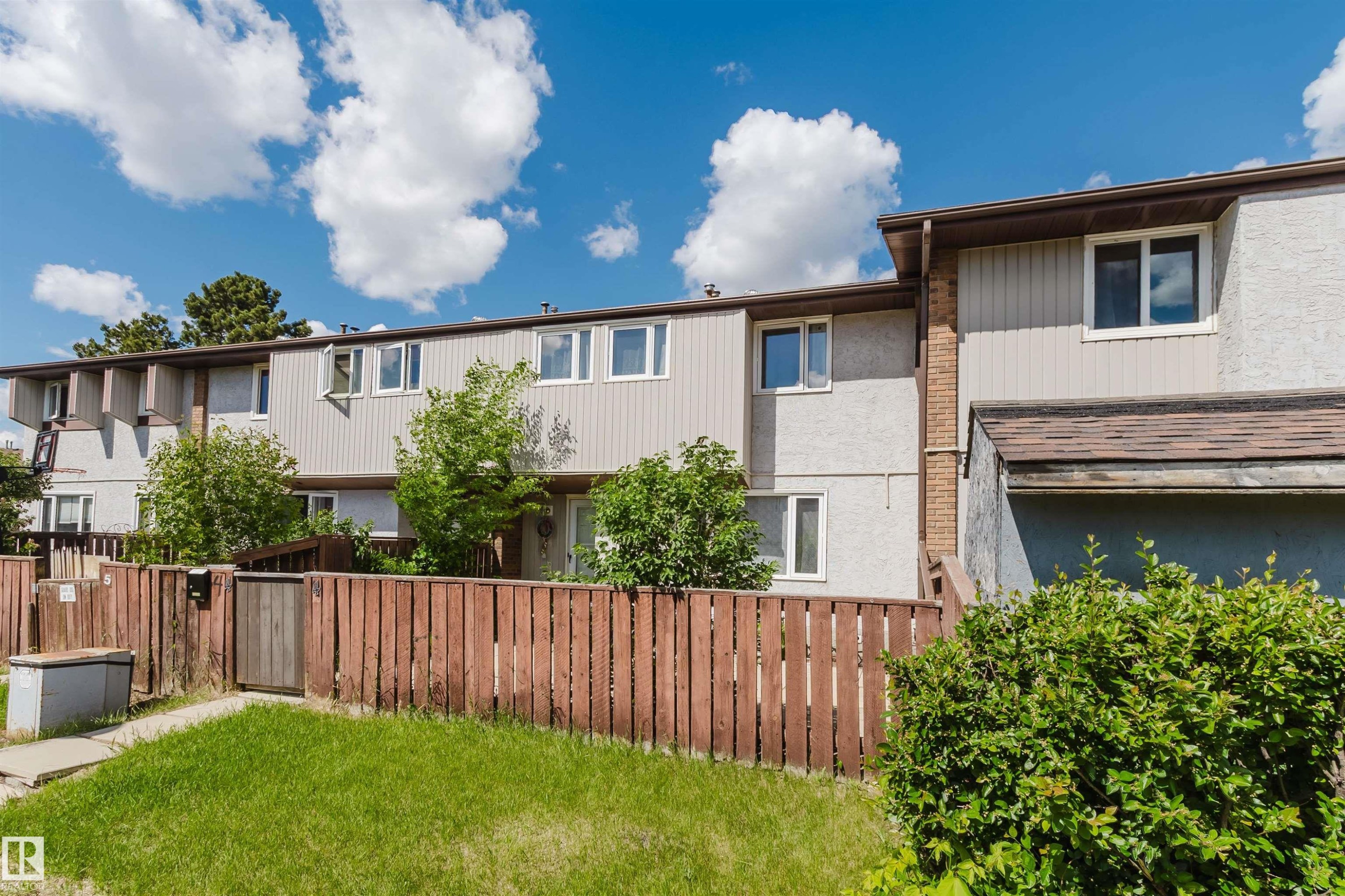 Townhouse exterior featuring vertical siding and stucco finishes - 4 14310 80 Street, Edmonton, AB