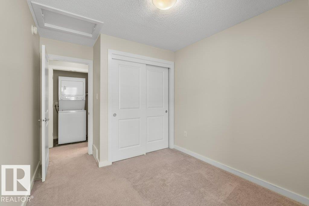 Light tan carpeted room featuring a white sliding closet door - 125 655 Watt Boulevard, Edmonton, AB