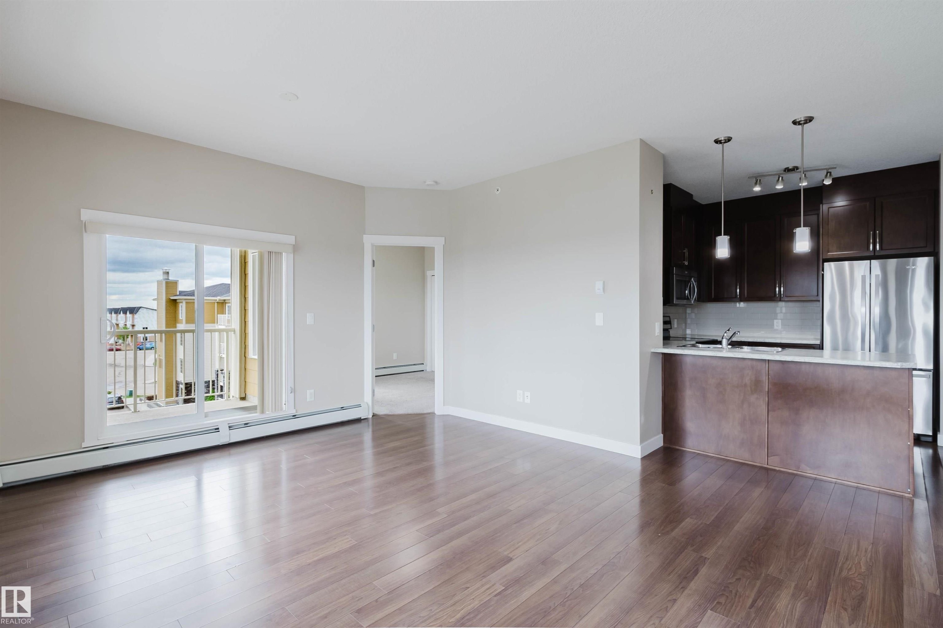 Open-concept living area featuring wood-finish flooring and neutral wall tones - 402 3670 139 Avenue, Edmonton, AB