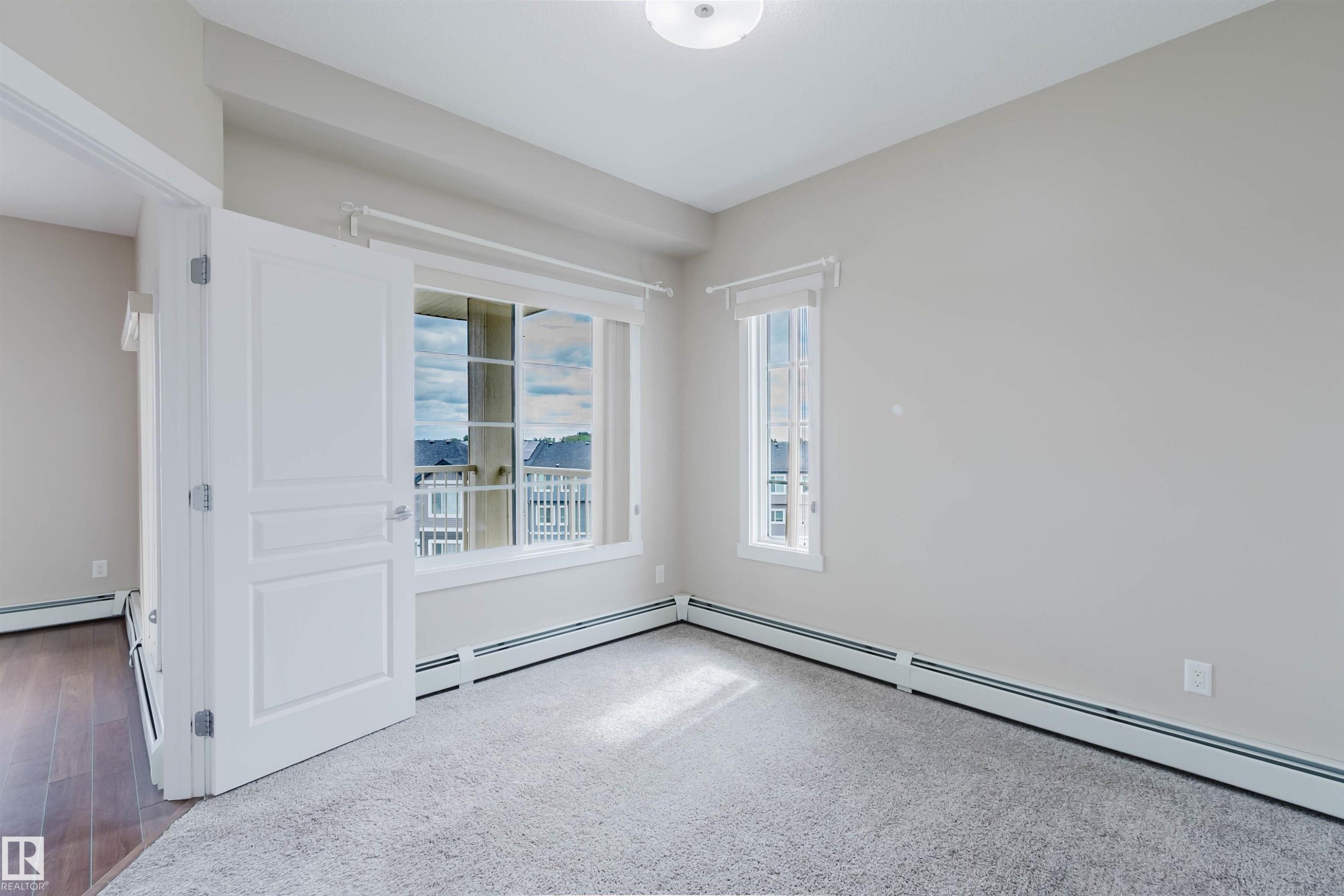Carpeted room with a large multi-pane window and a secondary vertical window - 402 3670 139 Avenue, Edmonton, AB