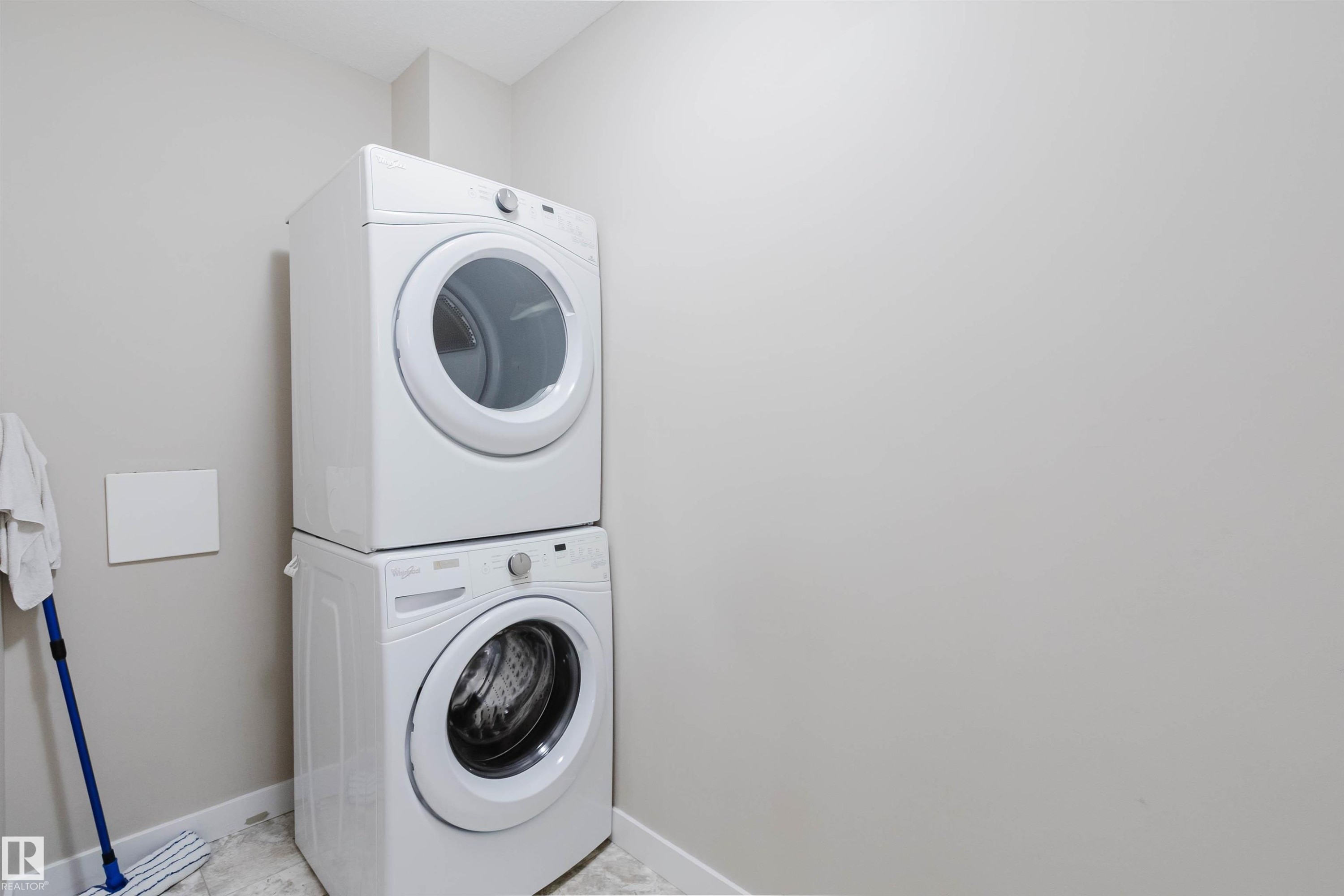 Dedicated laundry area featuring a white stackable washer and dryer set - 402 3670 139 Avenue, Edmonton, AB