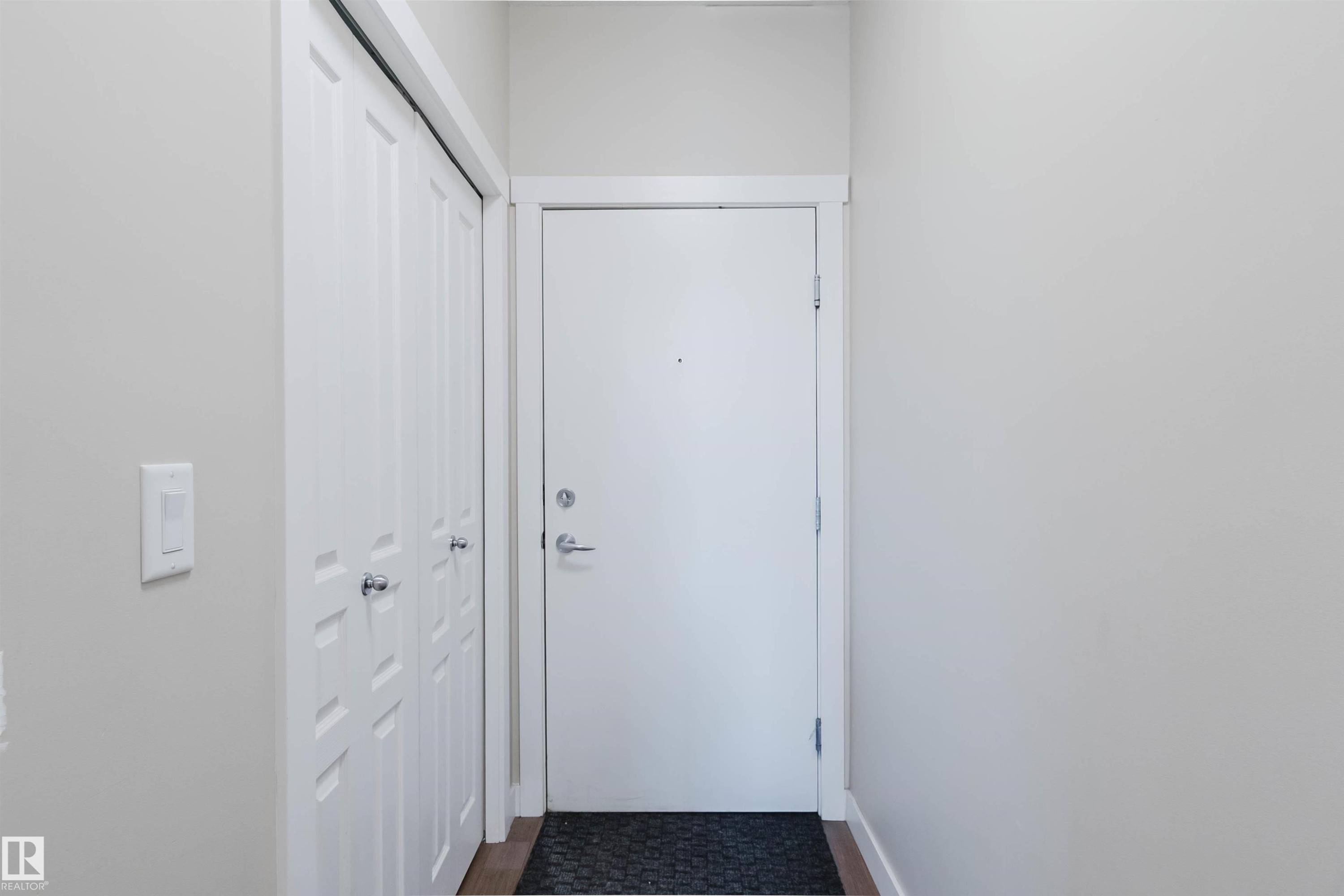 Entryway featuring a white door with brushed nickel hardware, light gray walls, and wood-finish flooring - 402 3670 139 Avenue, Edmonton, AB