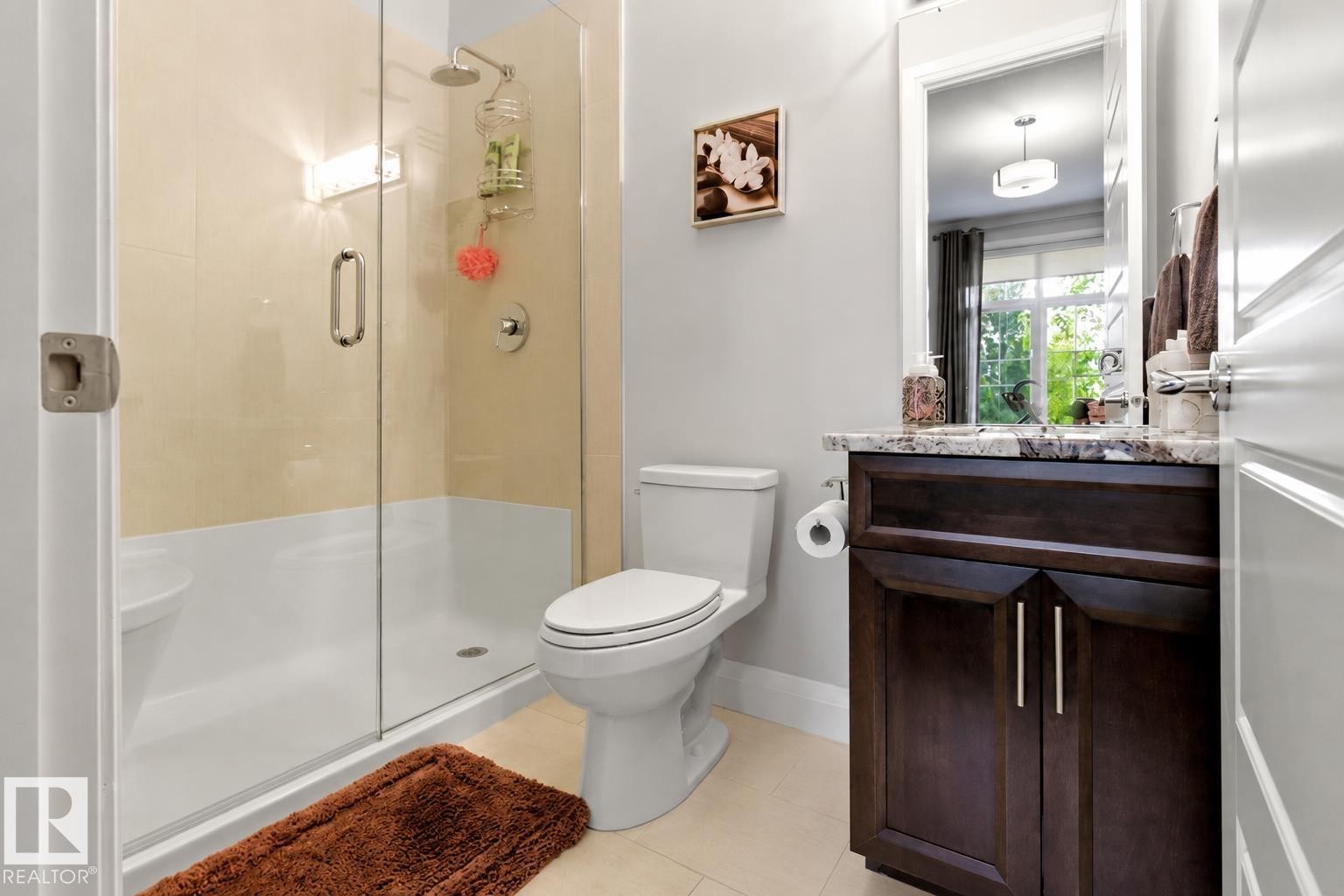 Full bathroom featuring a glass-enclosed shower with a rainfall showerhead, a dark wood-finish vanity with a stone countertop, a white rectangular undermount sink, and chrome fixtures - 9003 16 Avenue Sw, Edmonton, AB - Indoor Photo Showing Bathroom