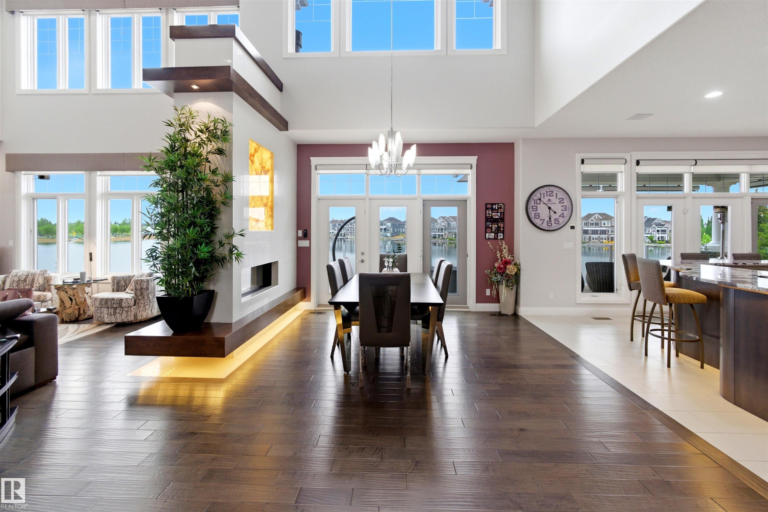 Expansive open-concept interior featuring wood-finish flooring, a contemporary fireplace with integrated lighting, and a dining area with multiple French doors - 9003 16 Avenue Sw, Edmonton, AB - Indoor Photo Showing Other Room