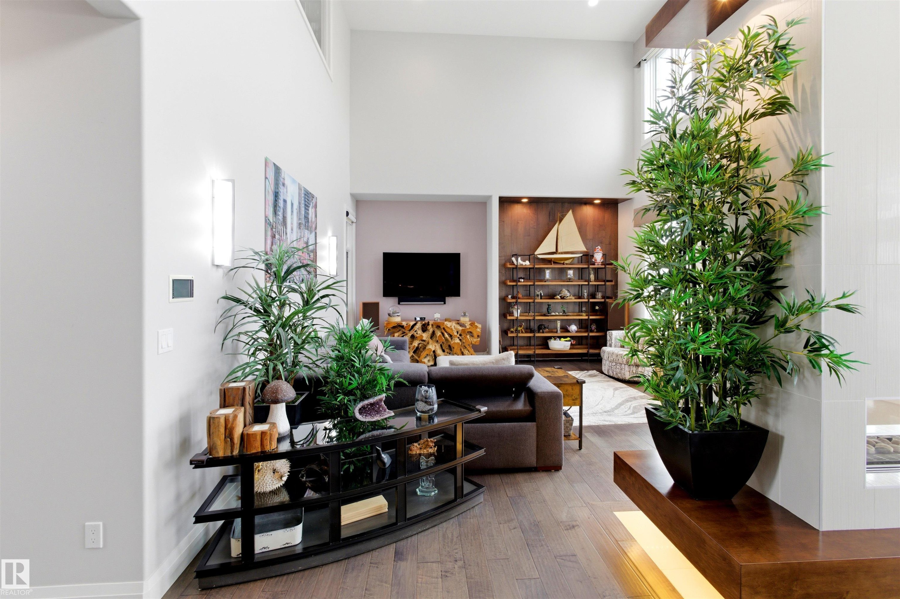 Spacious living area featuring high ceilings, wood-finish flooring, and built-in shelving with accent lighting - 9003 16 Avenue Sw, Edmonton, AB - Indoor Photo Showing Other Room
