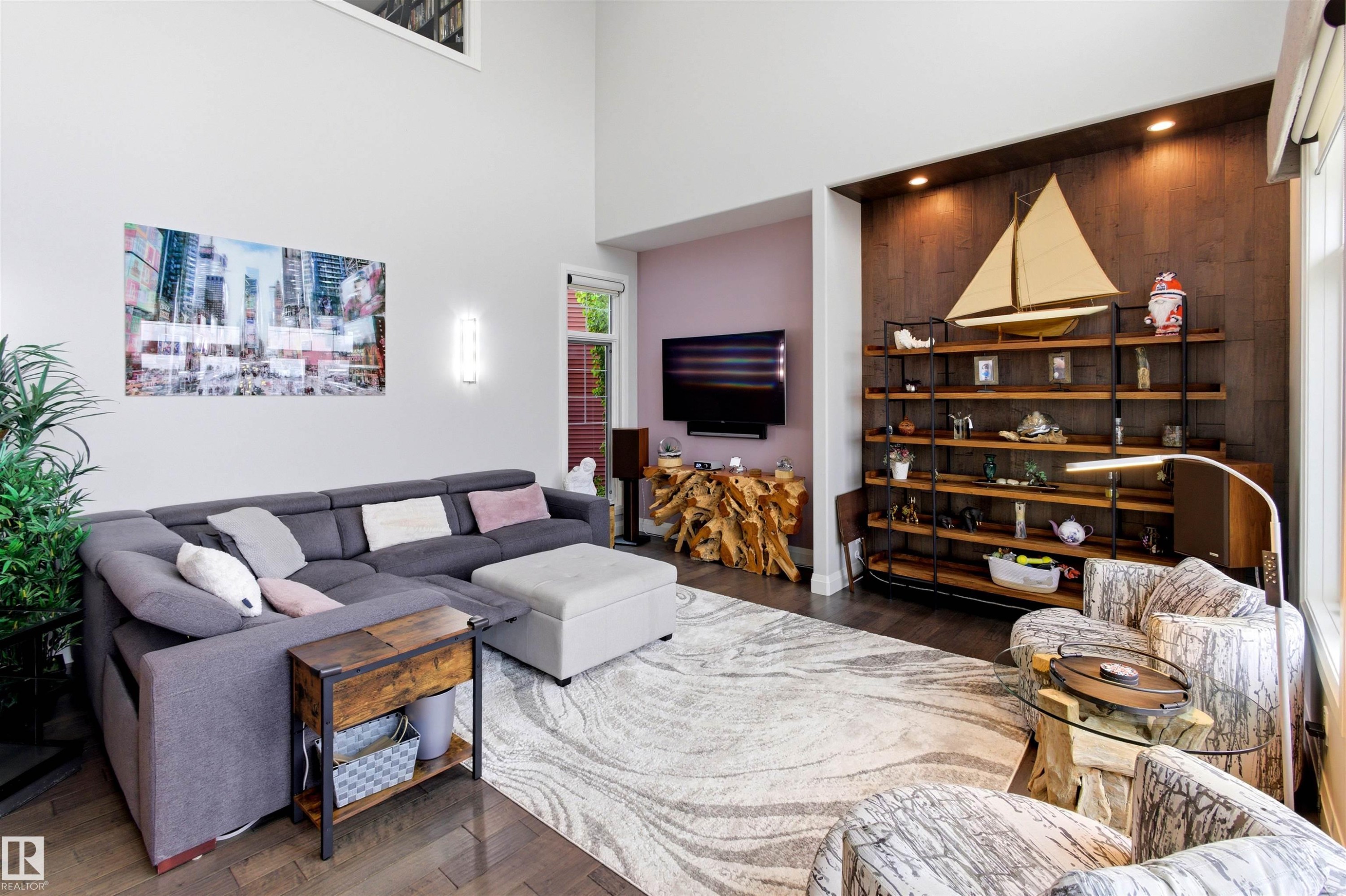 Spacious living area featuring high ceilings, dark wood-finish flooring, and a built-in recessed shelving unit with accent lighting - 9003 16 Avenue Sw, Edmonton, AB - Indoor Photo Showing Living Room
