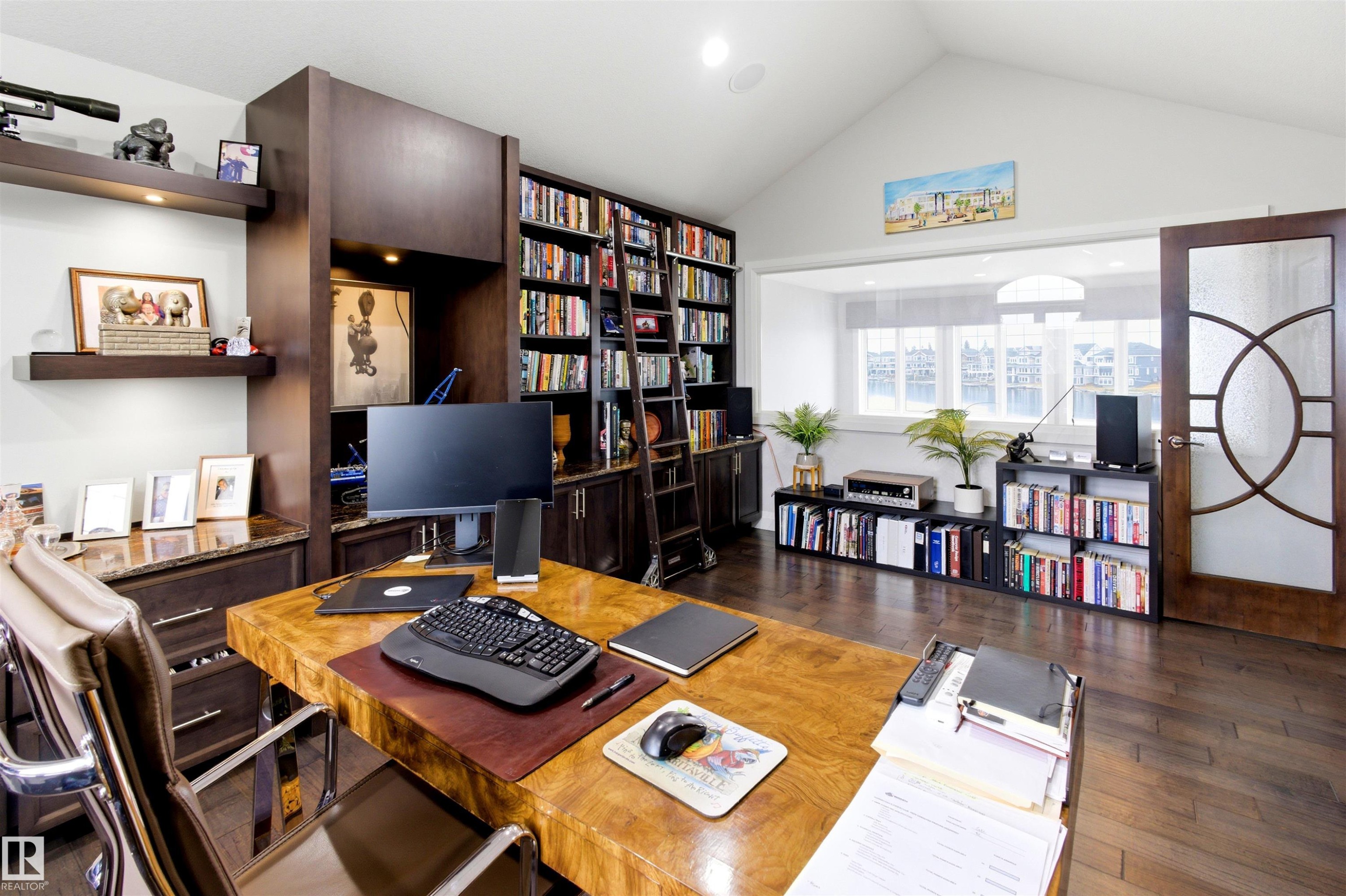 Spacious study featuring rich wood-finish flooring, built-in library shelving with a rolling ladder, and a vaulted ceiling - 9003 16 Avenue Sw, Edmonton, AB - Indoor Photo Showing Office