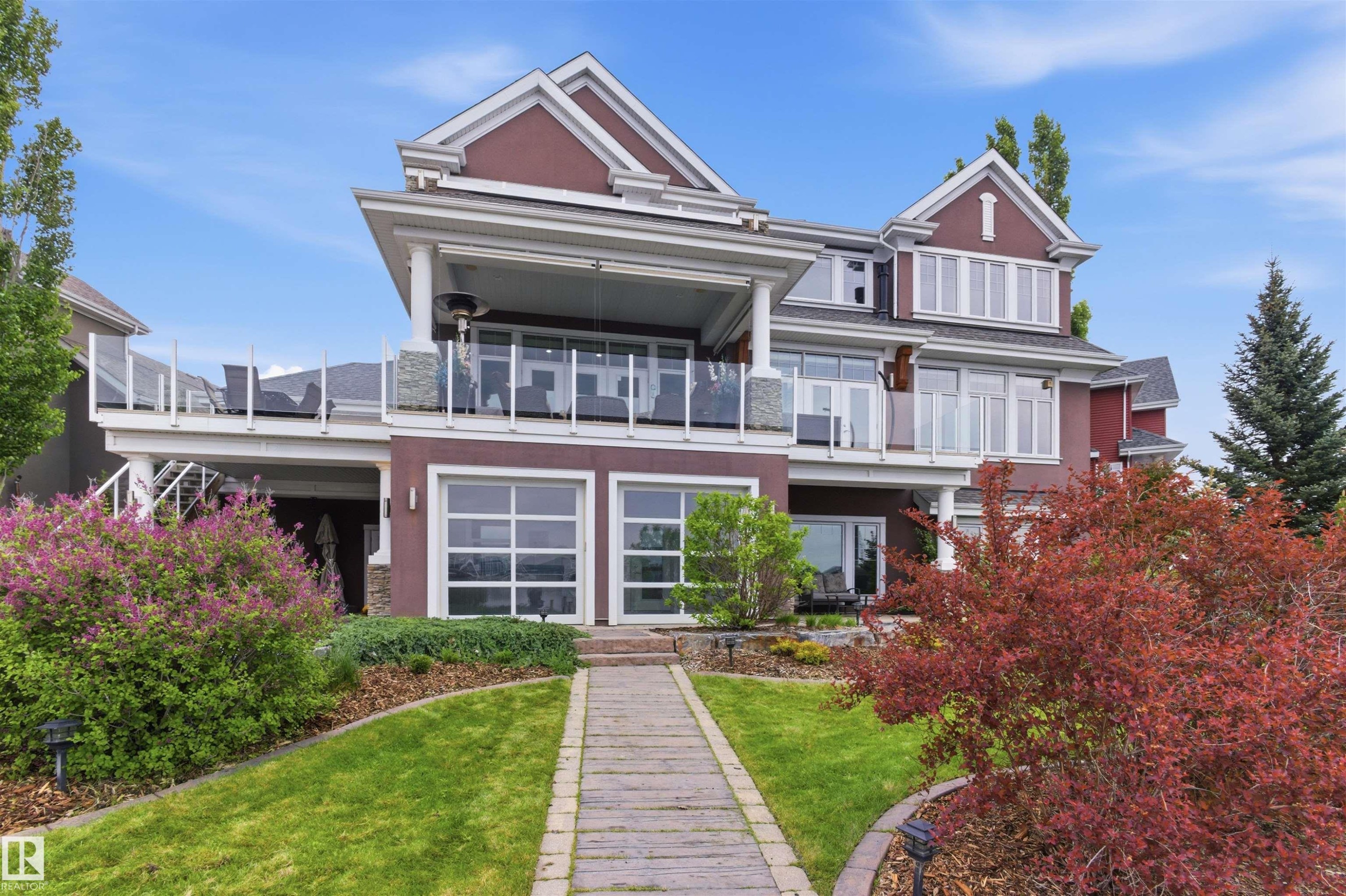Multi-level residence featuring a stone-clad walkway, manicured lawn, and mature landscaping - 9003 16 Avenue Sw, Edmonton, AB - Outdoor With Balcony With Facade