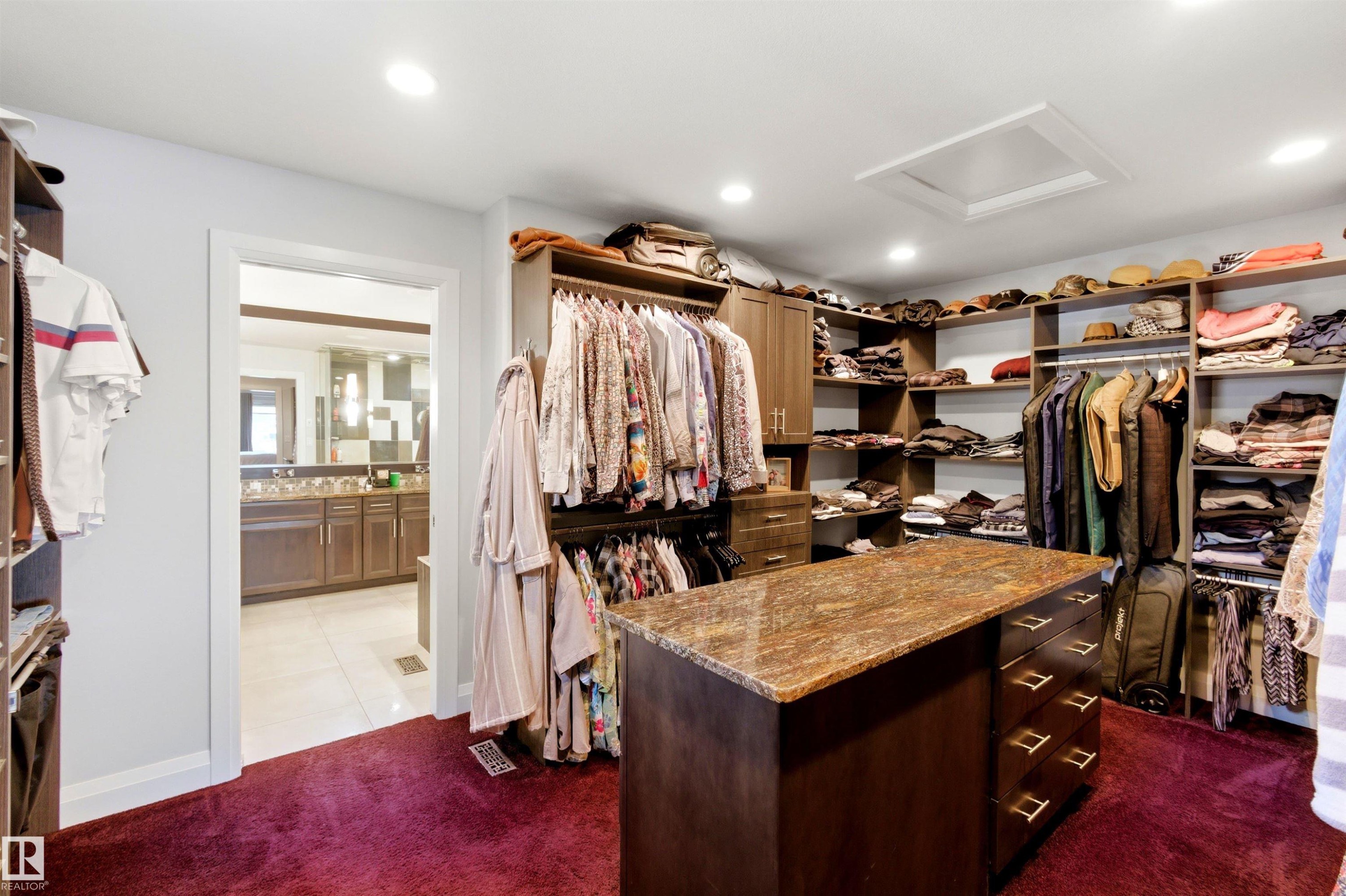 Walk-in closet featuring extensive built-in shelving, hanging rods, and a central island with a stone countertop - 9003 16 Avenue Sw, Edmonton, AB - Indoor With Storage
