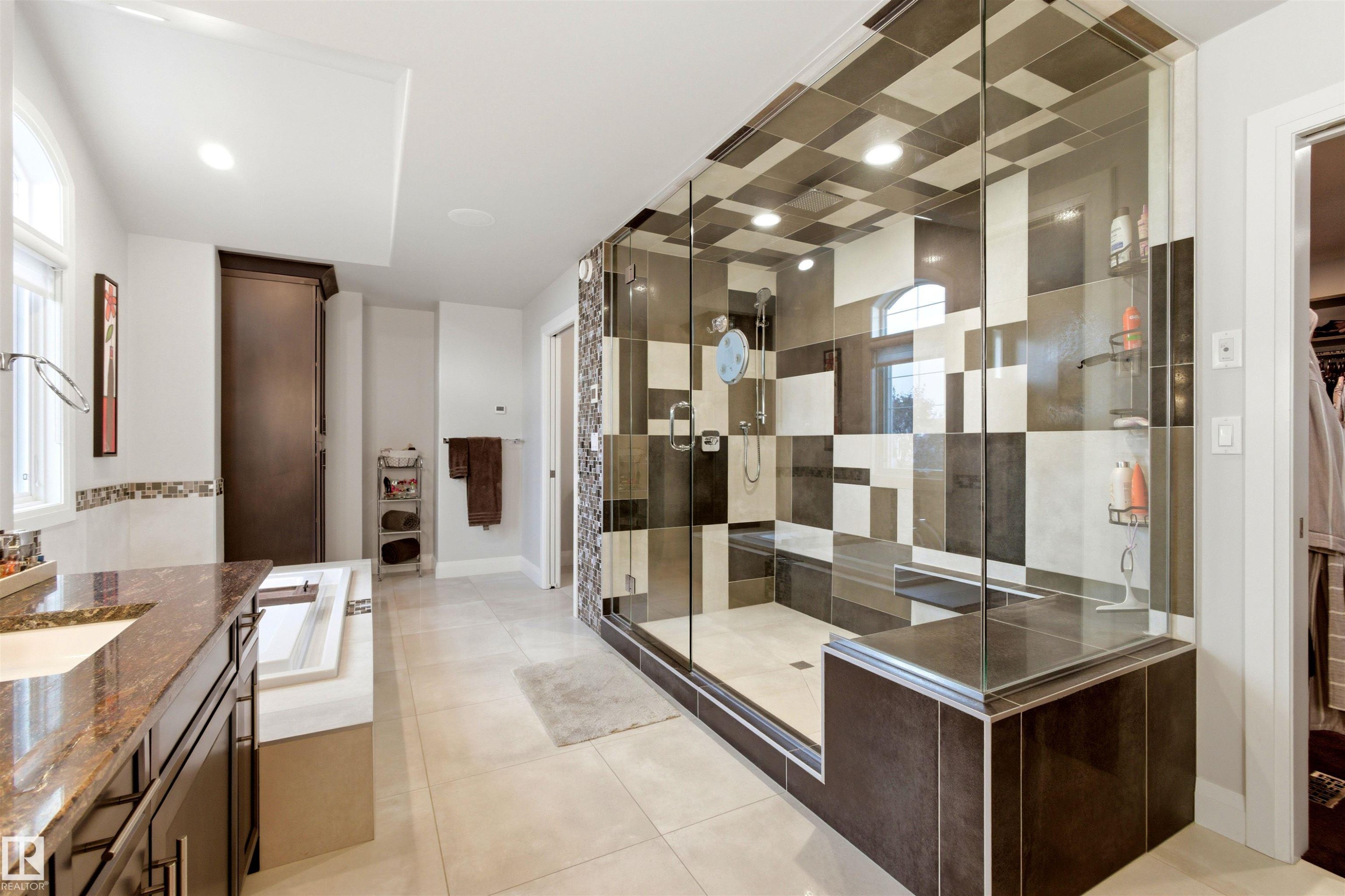 Expansive shower enclosure with glass panels, a built-in bench, and a unique checkerboard tile pattern extending to the ceiling - 9003 16 Avenue Sw, Edmonton, AB - Indoor