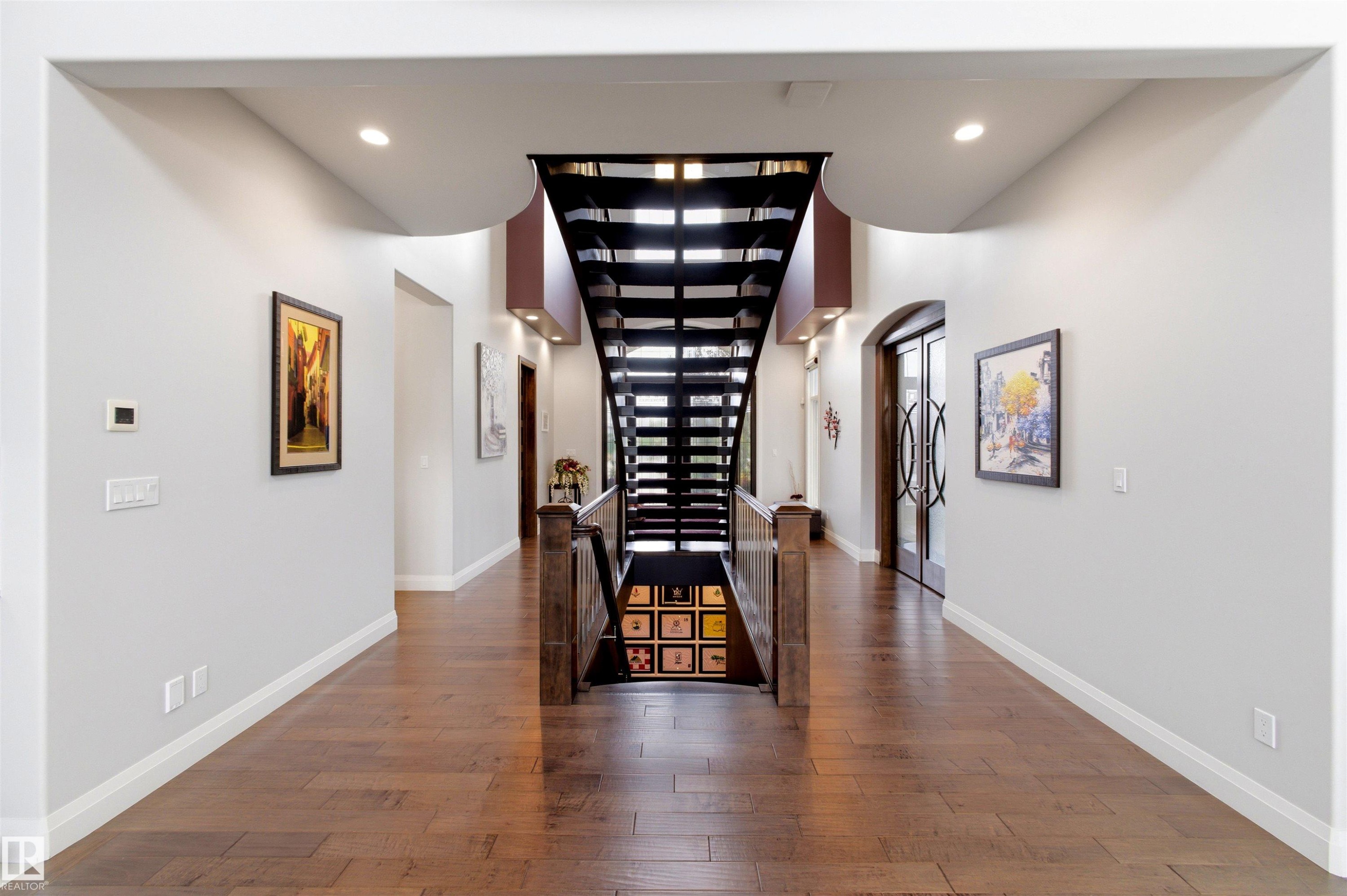 Central open-tread staircase with metal railing and wood-finish handrail, complemented by recessed lighting and wood-finish flooring - 9003 16 Avenue Sw, Edmonton, AB - Indoor Photo Showing Other Room
