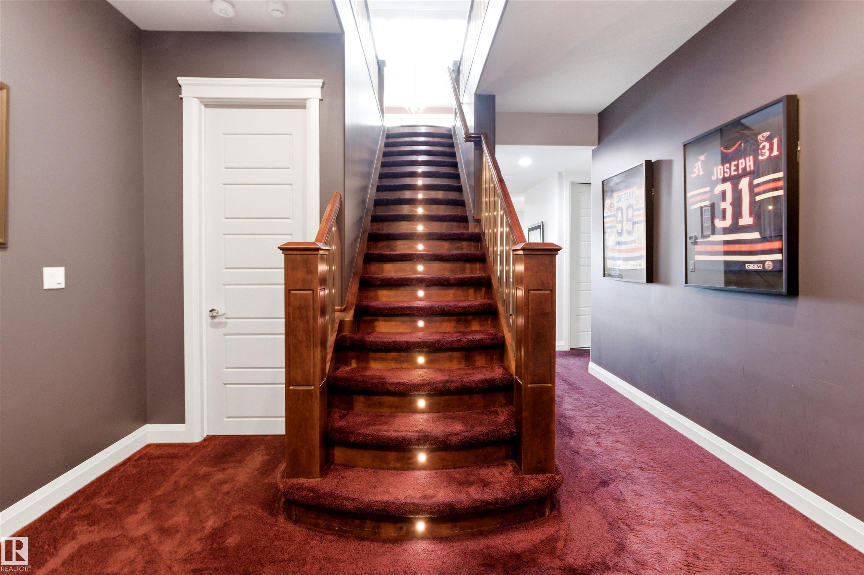 Curved staircase featuring recessed lighting on each tread, a wood-finish handrail, and rich red carpeting - 9003 16 Avenue Sw, Edmonton, AB - Indoor Photo Showing Other Room
