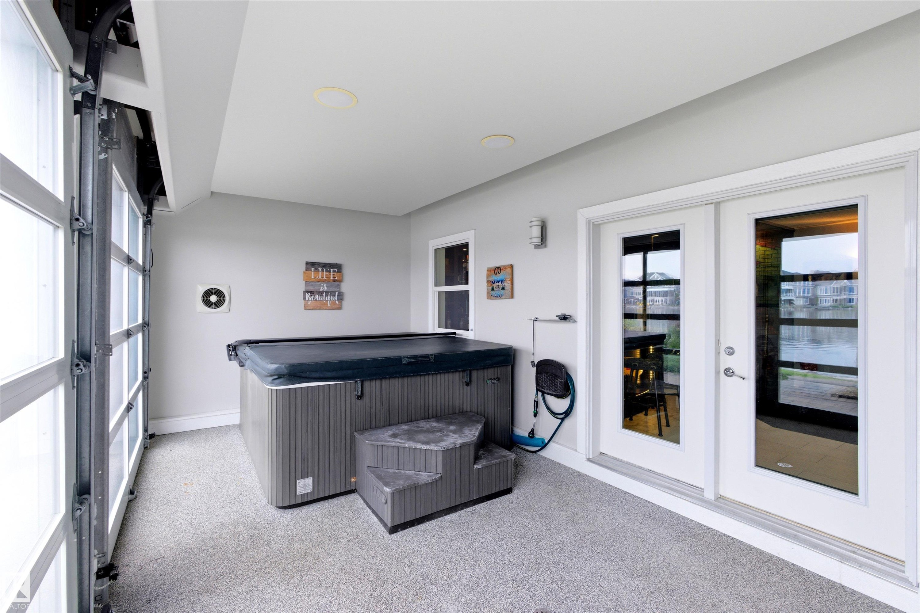 Covered patio with a spa, offering a lake backdrop through glass panel doors - 9003 16 Avenue Sw, Edmonton, AB - Indoor Photo Showing Other Room