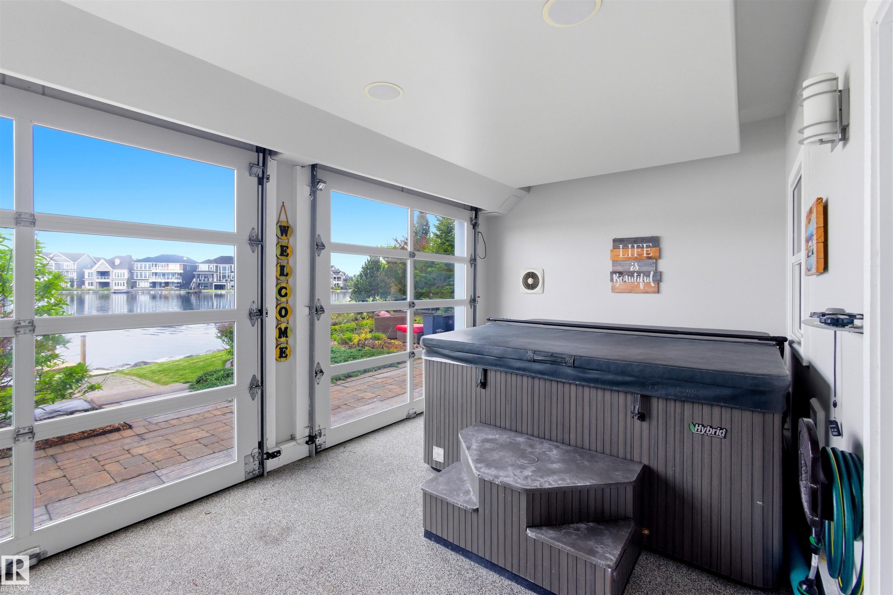 Indoor hot tub area featuring full-light overhead garage doors, a textured flooring finish, and recessed ceiling lighting - 9003 16 Avenue Sw, Edmonton, AB - Indoor