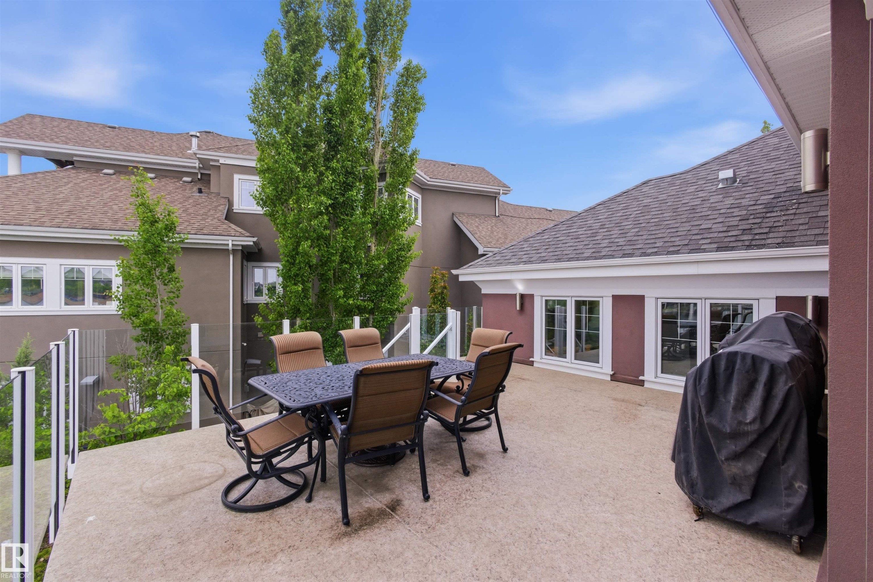 Expansive exterior deck featuring a concrete surface, glass panel railing, and multiple window accents - 9003 16 Avenue Sw, Edmonton, AB - Outdoor With Deck Patio Veranda With Exterior