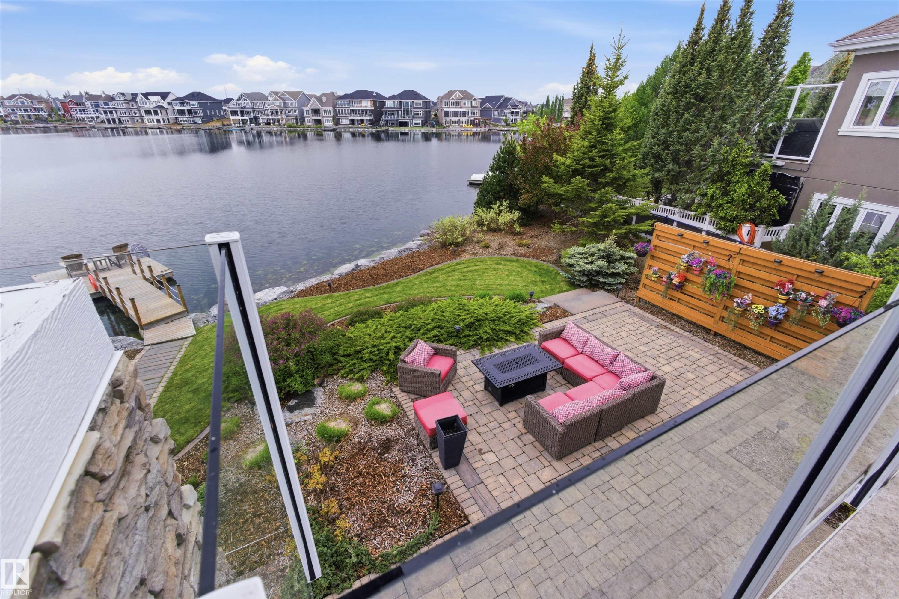 Waterfront property featuring a private dock, stone-clad lower exterior, and a paver patio - 9003 16 Avenue Sw, Edmonton, AB - Outdoor With Body Of Water