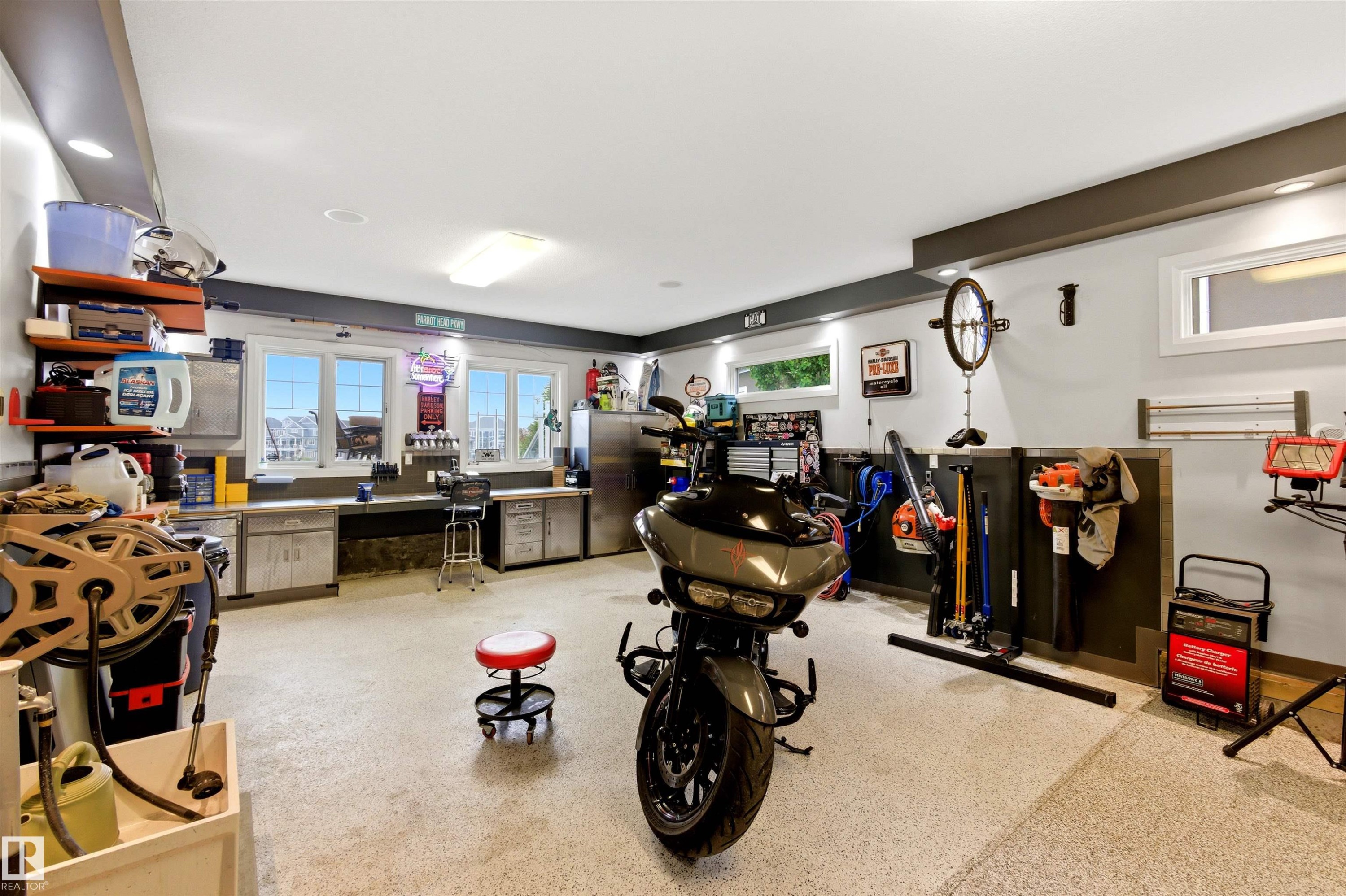 Spacious garage featuring an epoxy-coated concrete floor, abundant overhead lighting, and built-in workbench cabinetry - 9003 16 Avenue Sw, Edmonton, AB - Indoor