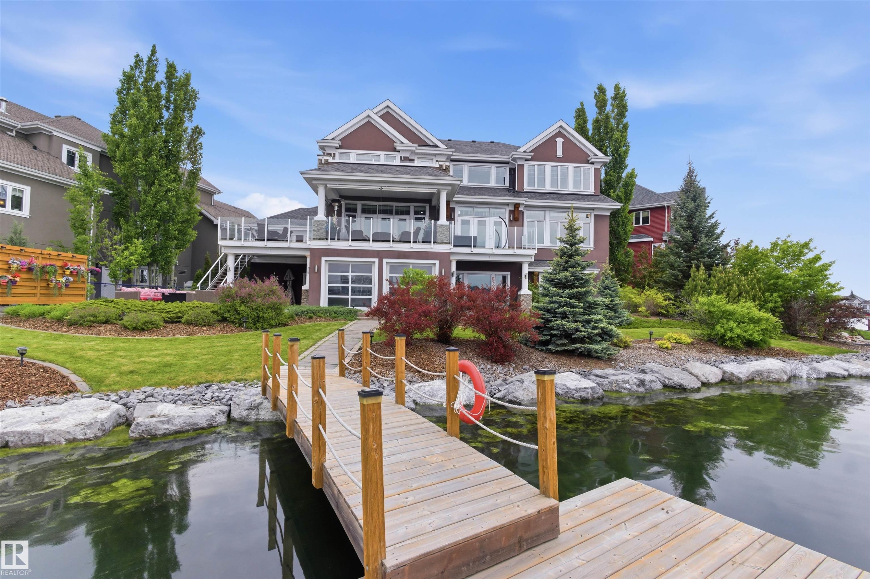 Waterfront property featuring a private wooden dock, manicured landscaping, and a multi-level deck with glass railings - 9003 16 Avenue Sw, Edmonton, AB - Outdoor With Body Of Water With Balcony With Deck Patio Veranda