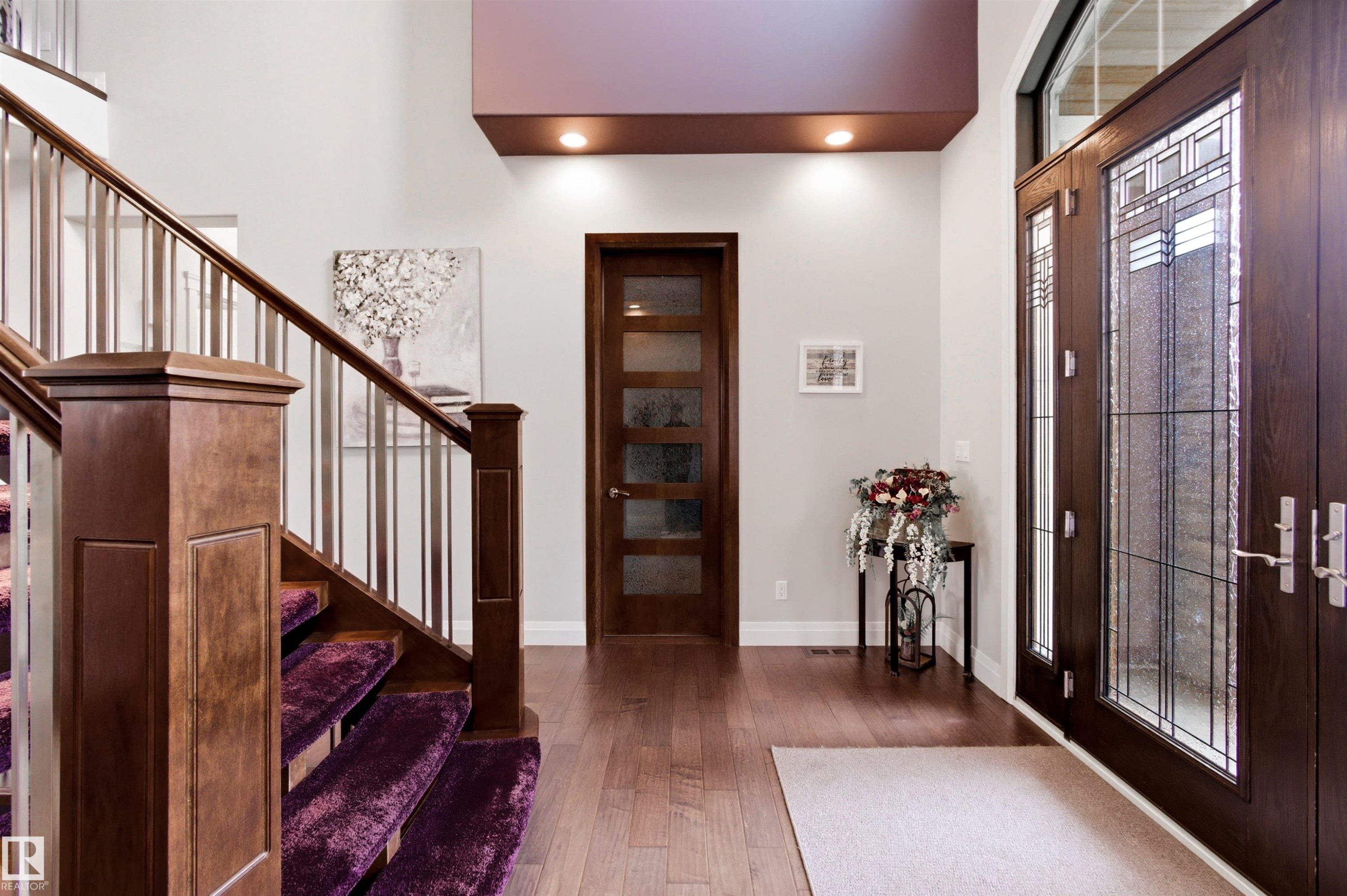 Grand entryway featuring double doors with decorative glass inserts, hardwood flooring, a staircase with wood newel posts and metal balusters, a recessed ceiling detail with integrated lighting, and a solid wood door with frosted glass panels - 9003 16 Avenue Sw, Edmonton, AB - Indoor Photo Showing Other Room