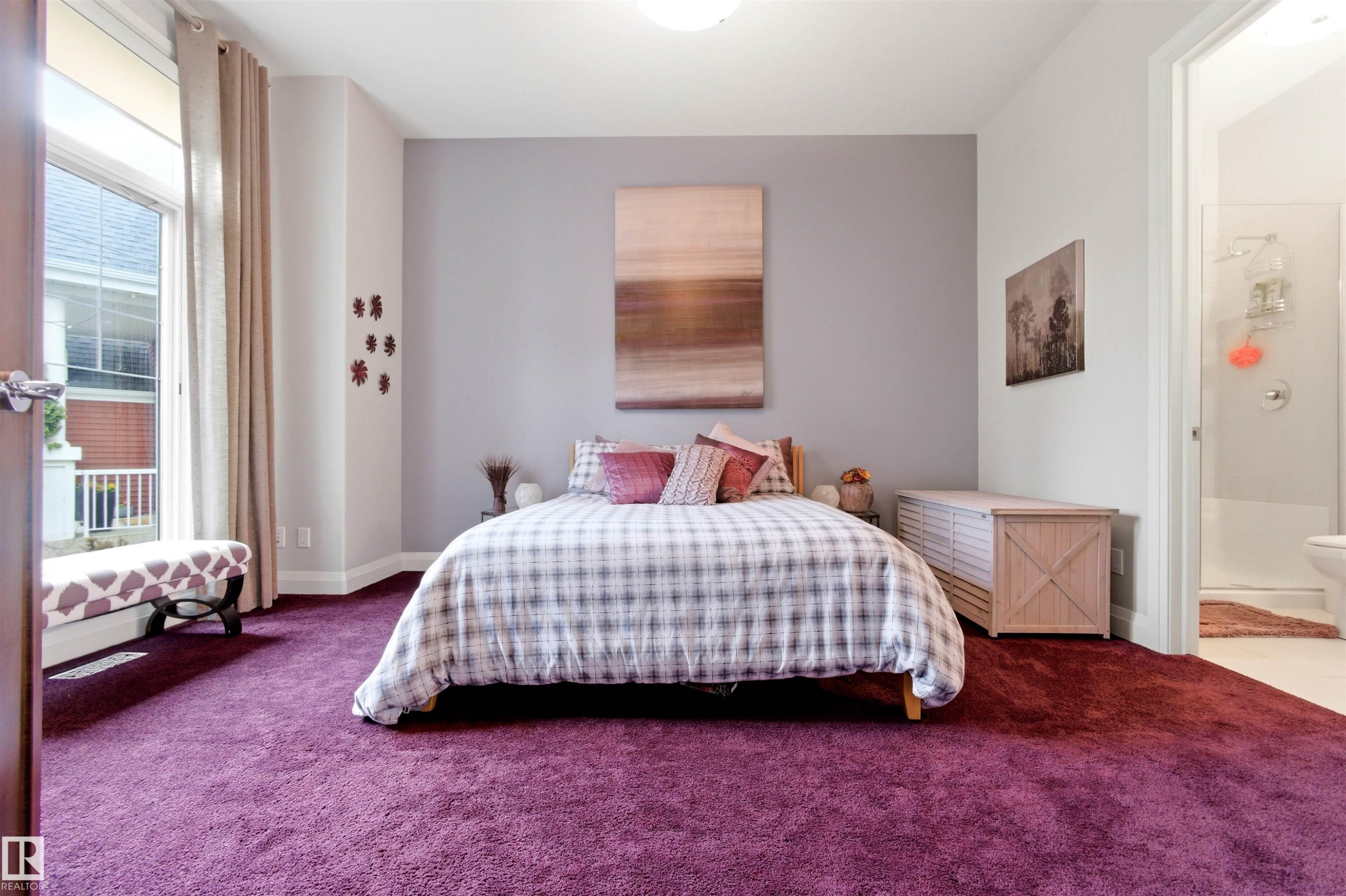 Plush purple carpeting grounds this room featuring a large window with white trim, light gray walls, and an attached bathroom with a shower and toilet - 9003 16 Avenue Sw, Edmonton, AB - Indoor Photo Showing Bedroom