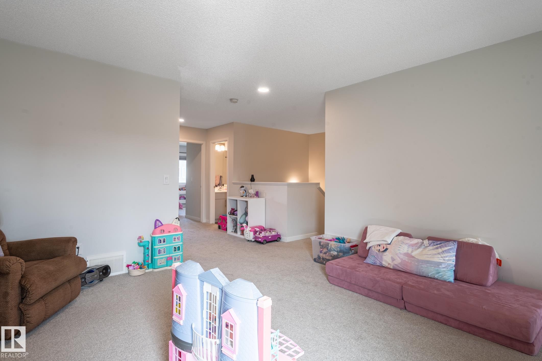 Carpeted interior space featuring light neutral wall paint, recessed lighting, and a partial balustrade - 17562 63A Street, Edmonton, AB