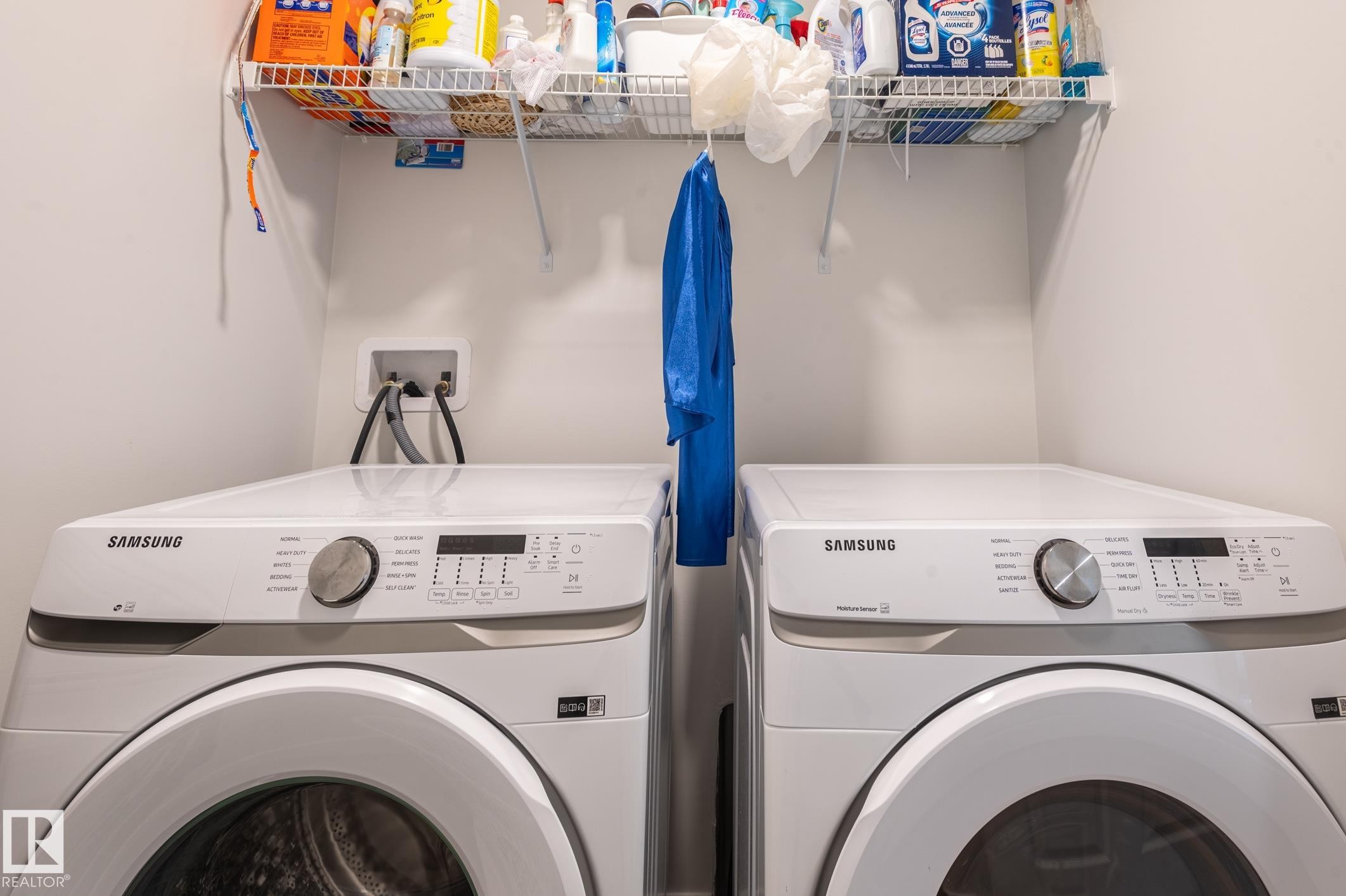 Dedicated laundry area featuring a front-loading washer and dryer set, overhead wire shelving, and neutral wall finishes - 17562 63A Street, Edmonton, AB