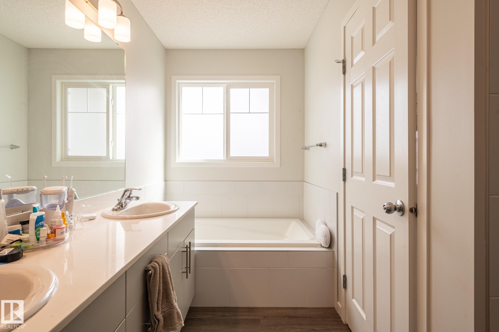 Bathroom featuring a double vanity with light-toned countertops, undermount sinks, and contemporary cabinetry - 17562 63A Street, Edmonton, AB