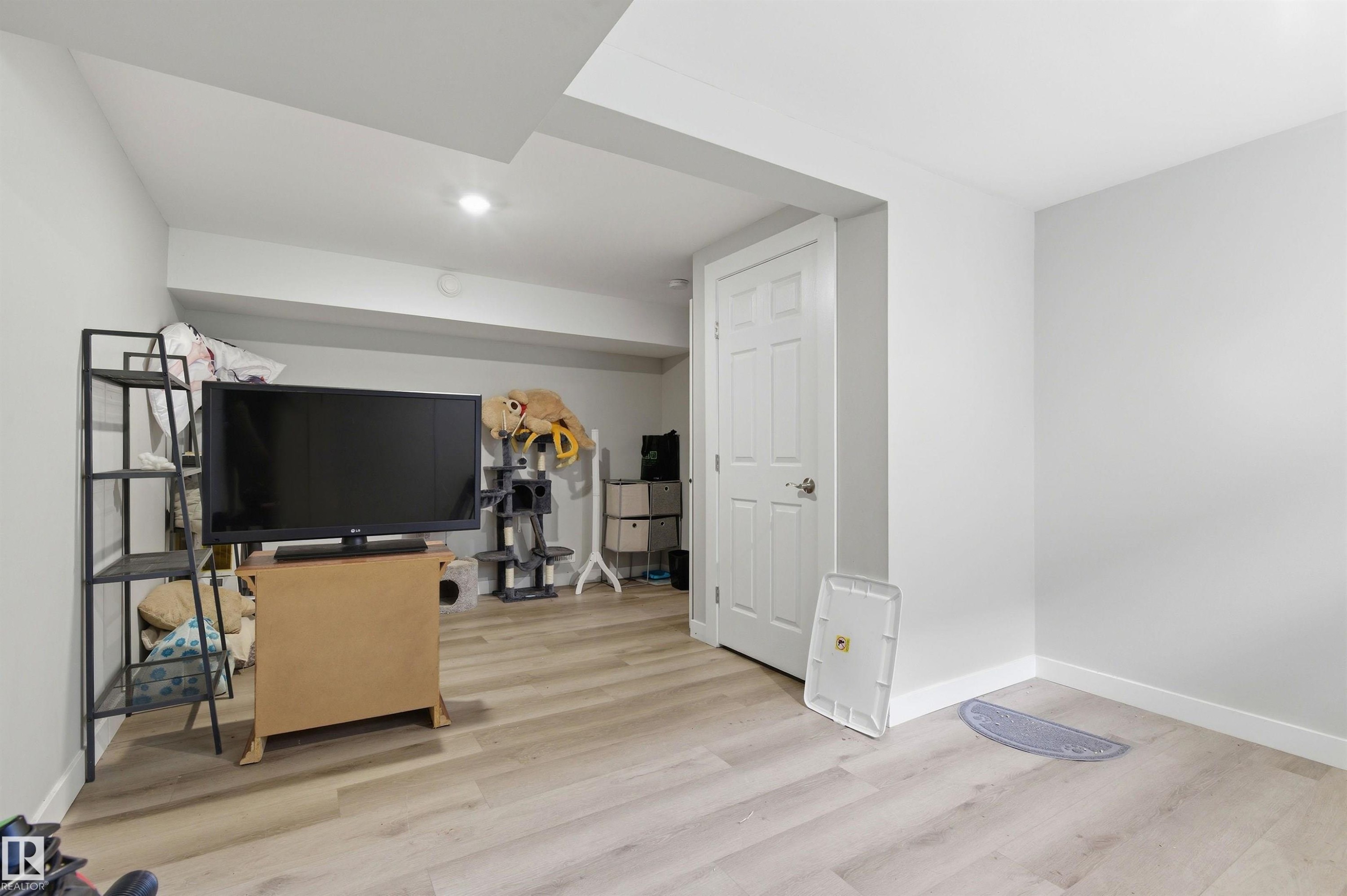 Spacious room featuring light wood-finish flooring, recessed lighting, and crisp white walls - 7412/7414 83 Avenue Nw, Edmonton, AB - Indoor