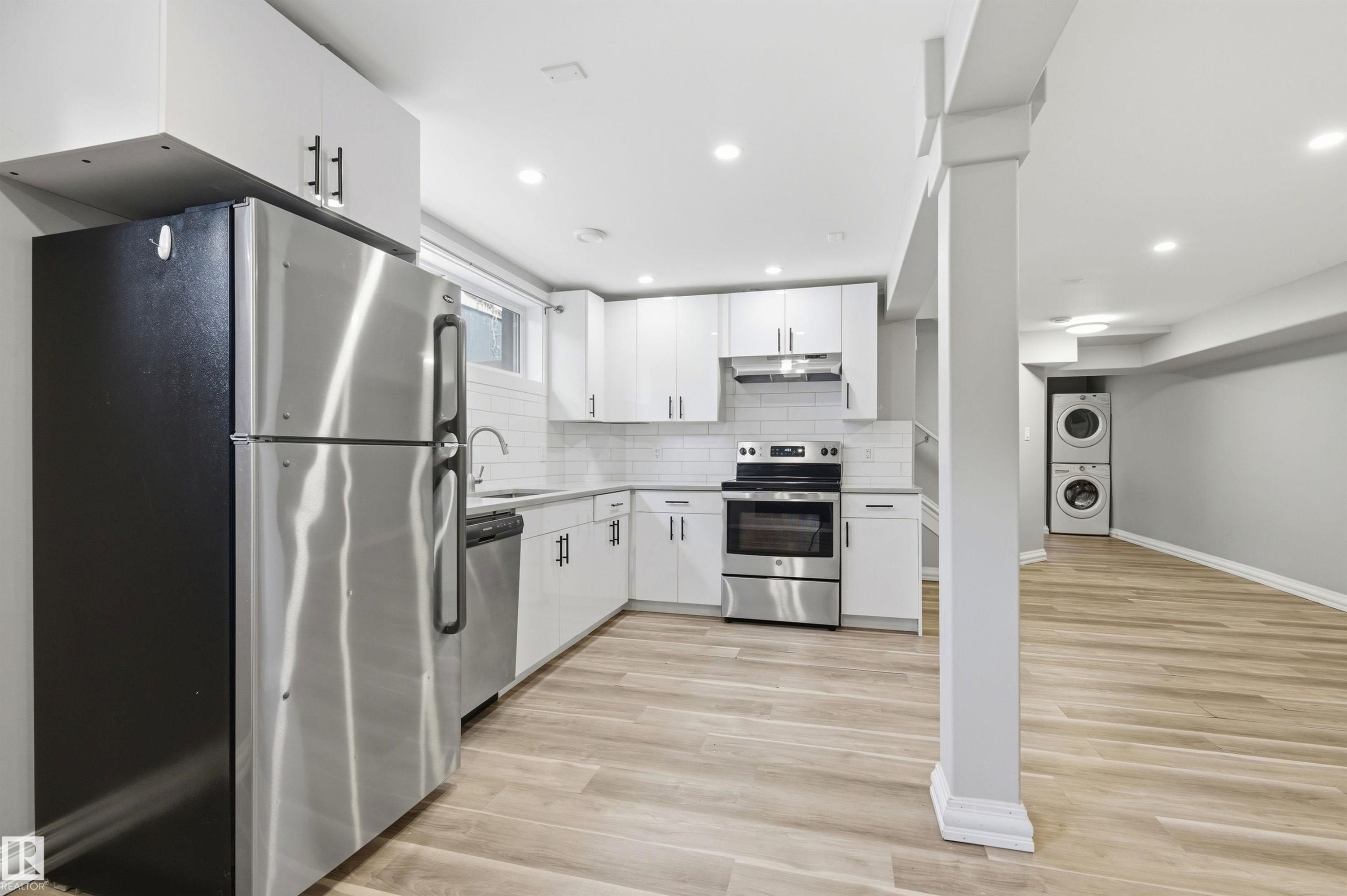 Modern kitchen featuring white cabinetry, stainless steel appliances, light wood-finish flooring, recessed lighting, and a subway tile backsplash - 7412/7414 83 Avenue Nw, Edmonton, AB - Indoor Photo Showing Kitchen With Upgraded Kitchen
