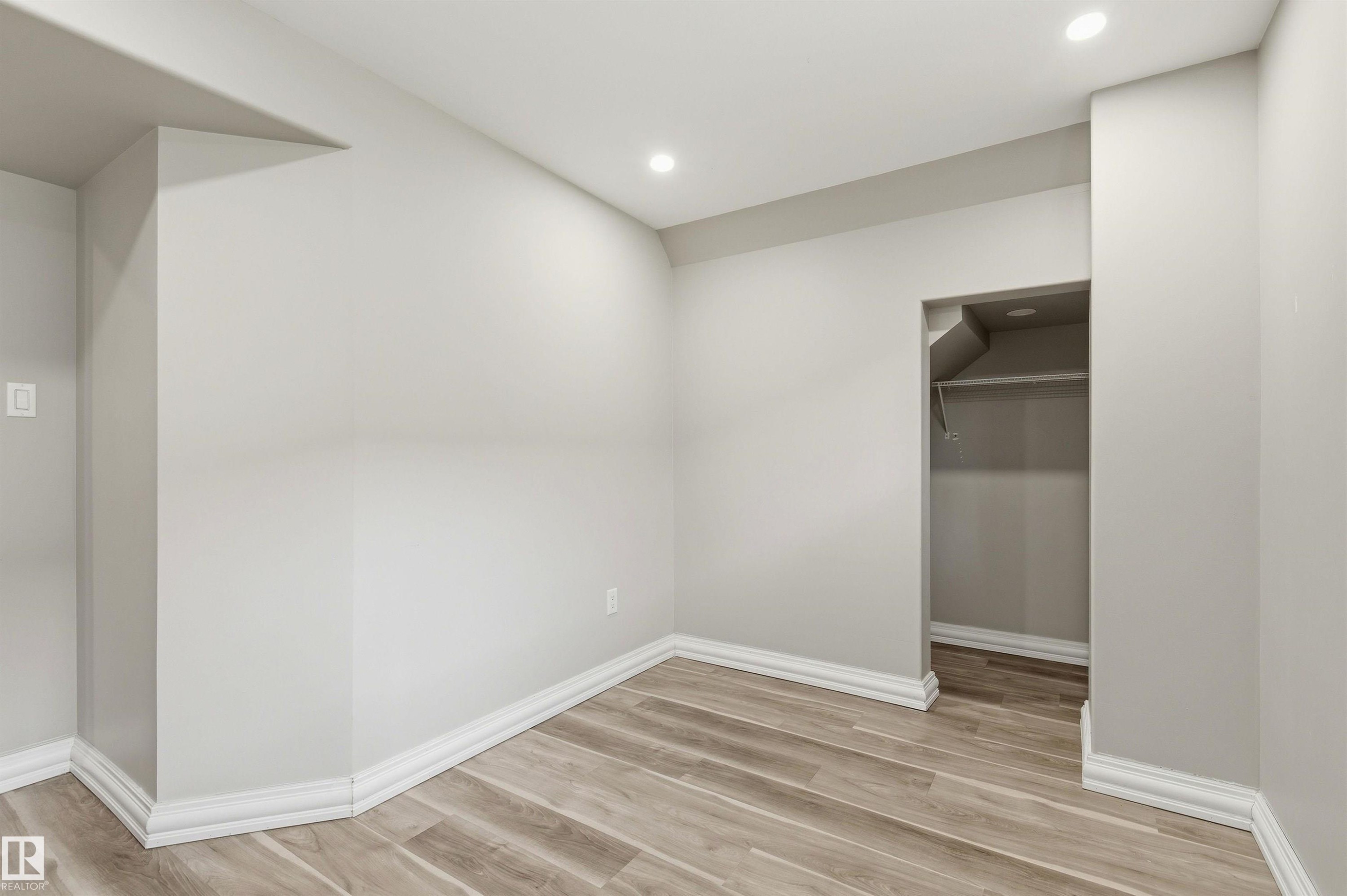 Room featuring recessed lighting, wood-finish flooring, light gray wall paint, and white baseboards - 7412/7414 83 Avenue Nw, Edmonton, AB - Indoor Photo Showing Other Room