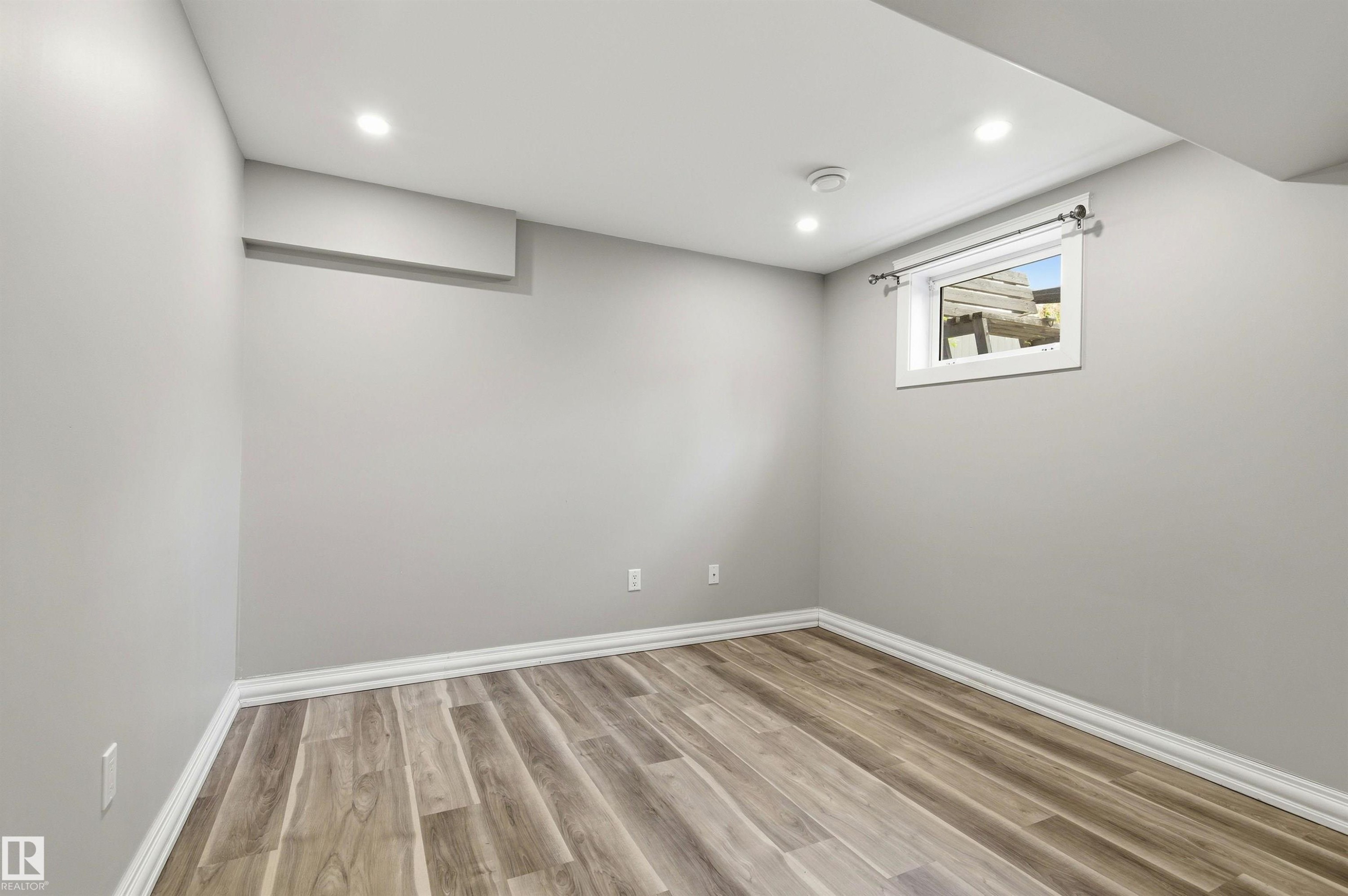 Room featuring wood-finish flooring, recessed lighting, and a white-trimmed window - 7412/7414 83 Avenue Nw, Edmonton, AB - Indoor Photo Showing Other Room