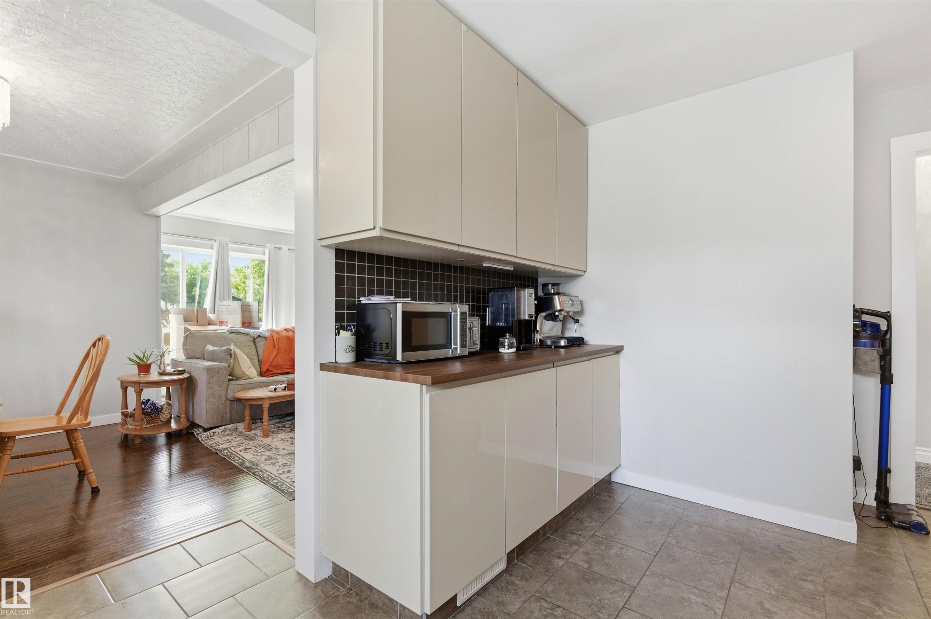 Kitchenette featuring slab-front cabinetry, wood-finish countertop, and dark tile backsplash - 7412/7414 83 Avenue Nw, Edmonton, AB - Indoor Photo Showing Kitchen