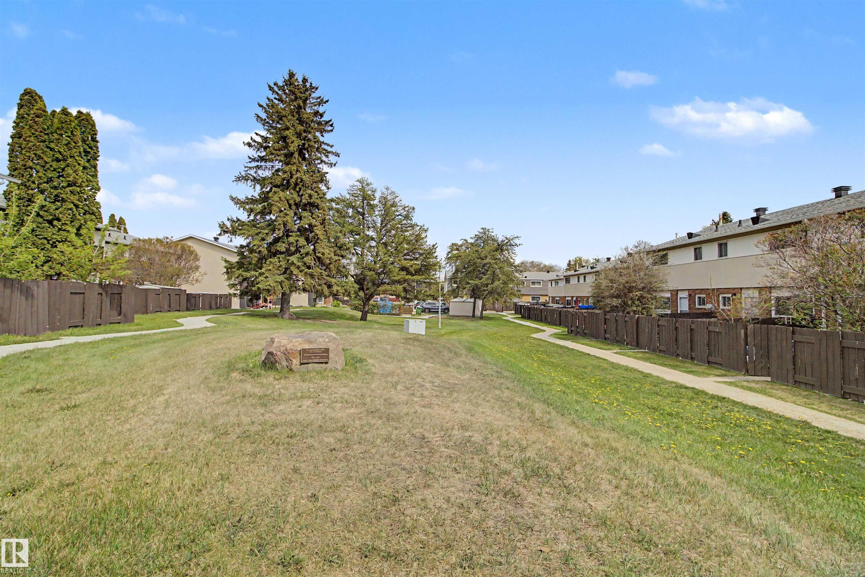 Expansive green space featuring a walking path, mature trees, and a commemorative stone - 5724 143 Avenue, Edmonton, AB