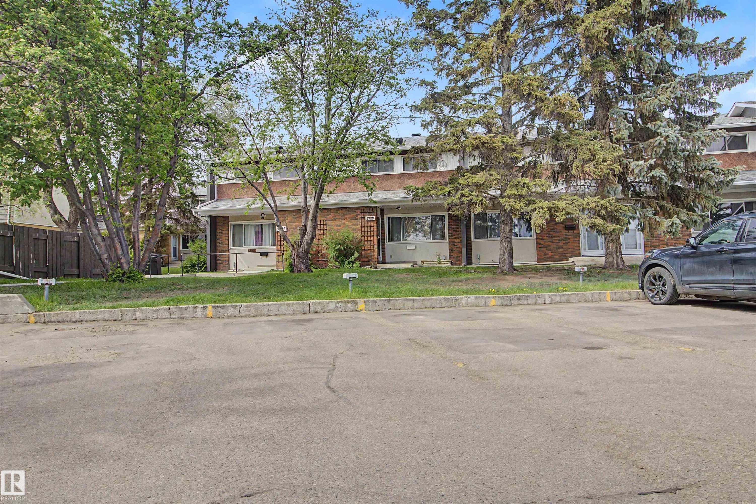 Brick exterior townhomes featuring multiple windows and mature trees - 5724 143 Avenue, Edmonton, AB