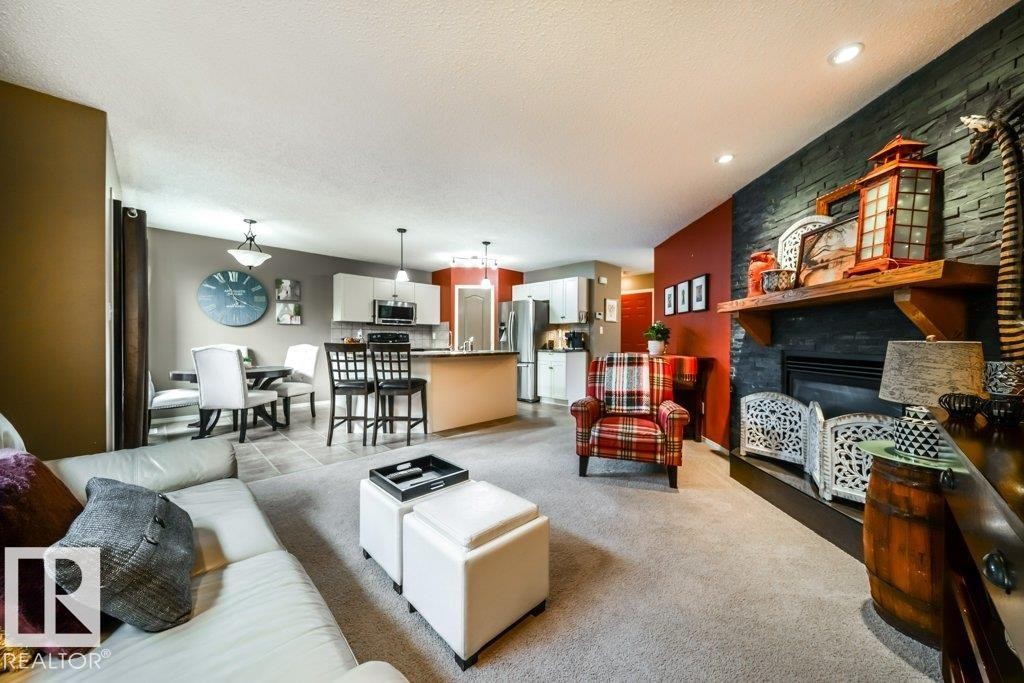 Spacious living area featuring a stone accent wall with a built-in fireplace, a wood mantel, and recessed lighting - 8507 2 Avenue Sw, Edmonton, AB - Indoor Photo Showing Living Room