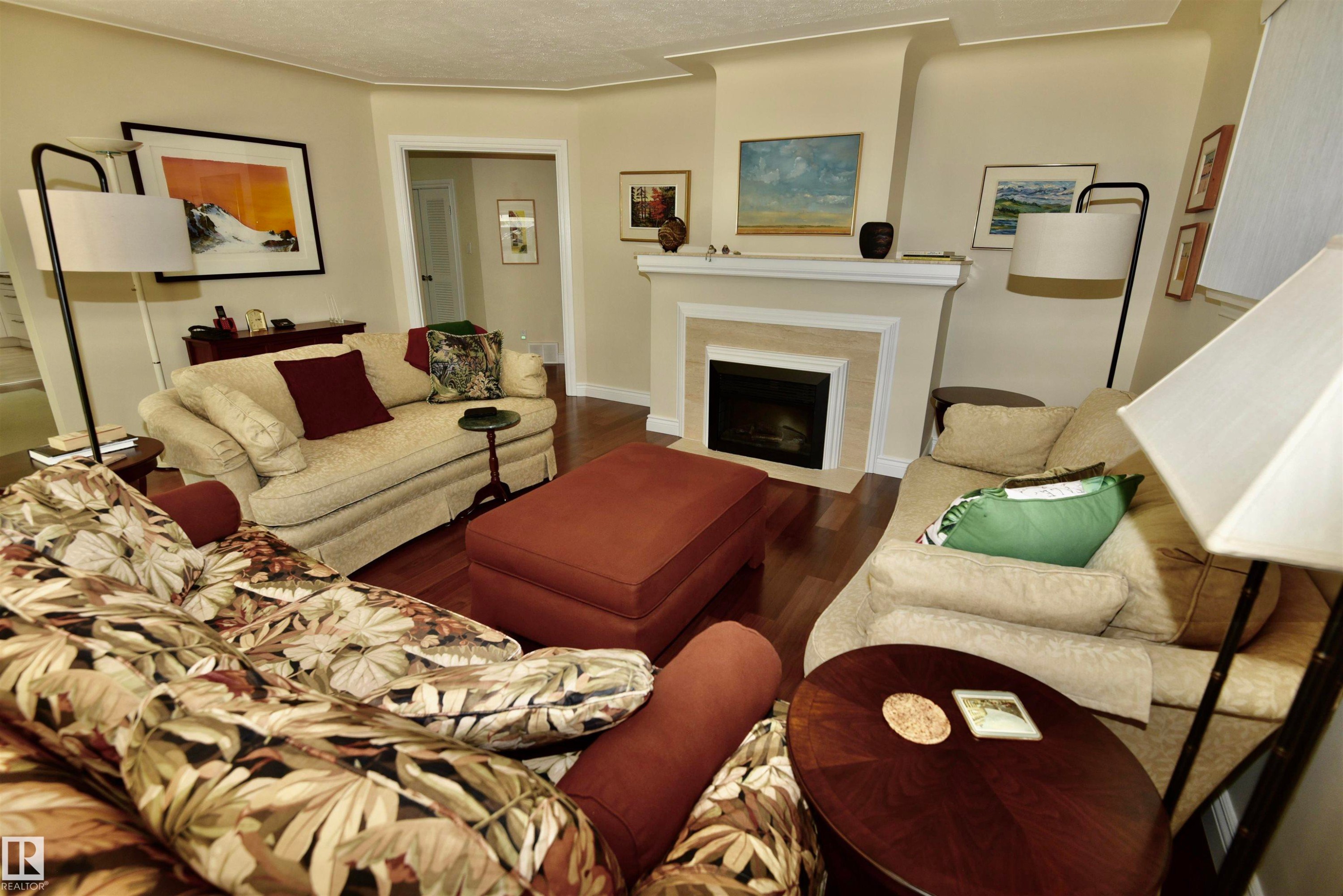 Living area featuring wood-finish flooring, a white mantel, and a built-in fireplace - 6 St George'S Crescent, Edmonton, AB