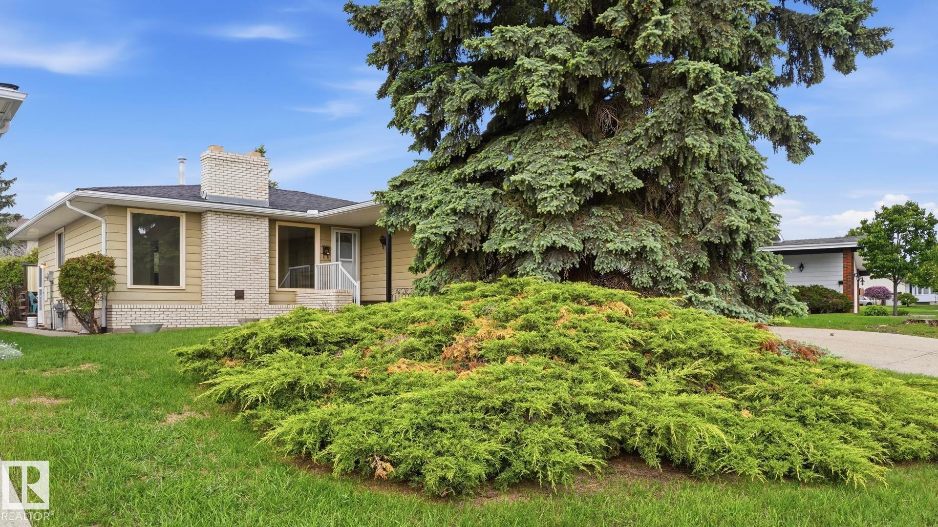 Exterior featuring pale yellow siding, white brick accents, and a dark roof - 7408 40 Avenue, Edmonton, AB