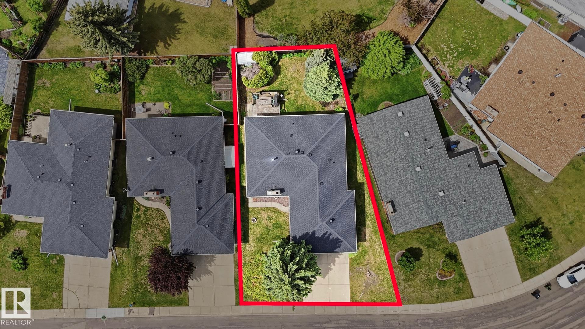 Property featuring a dark shingle roof, a concrete driveway, and a partially fenced backyard with mature trees - 7408 40 Avenue, Edmonton, AB