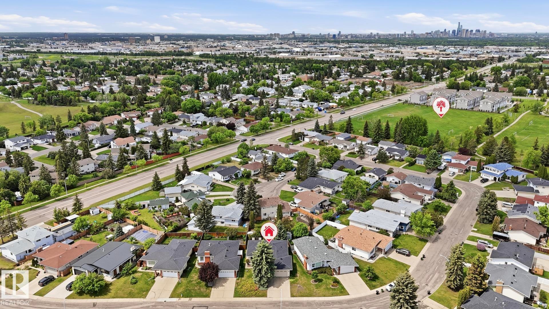 Aerial perspective showcasing a residential neighborhood with detached homes, mature trees, and a nearby roadway - 7408 40 Avenue, Edmonton, AB