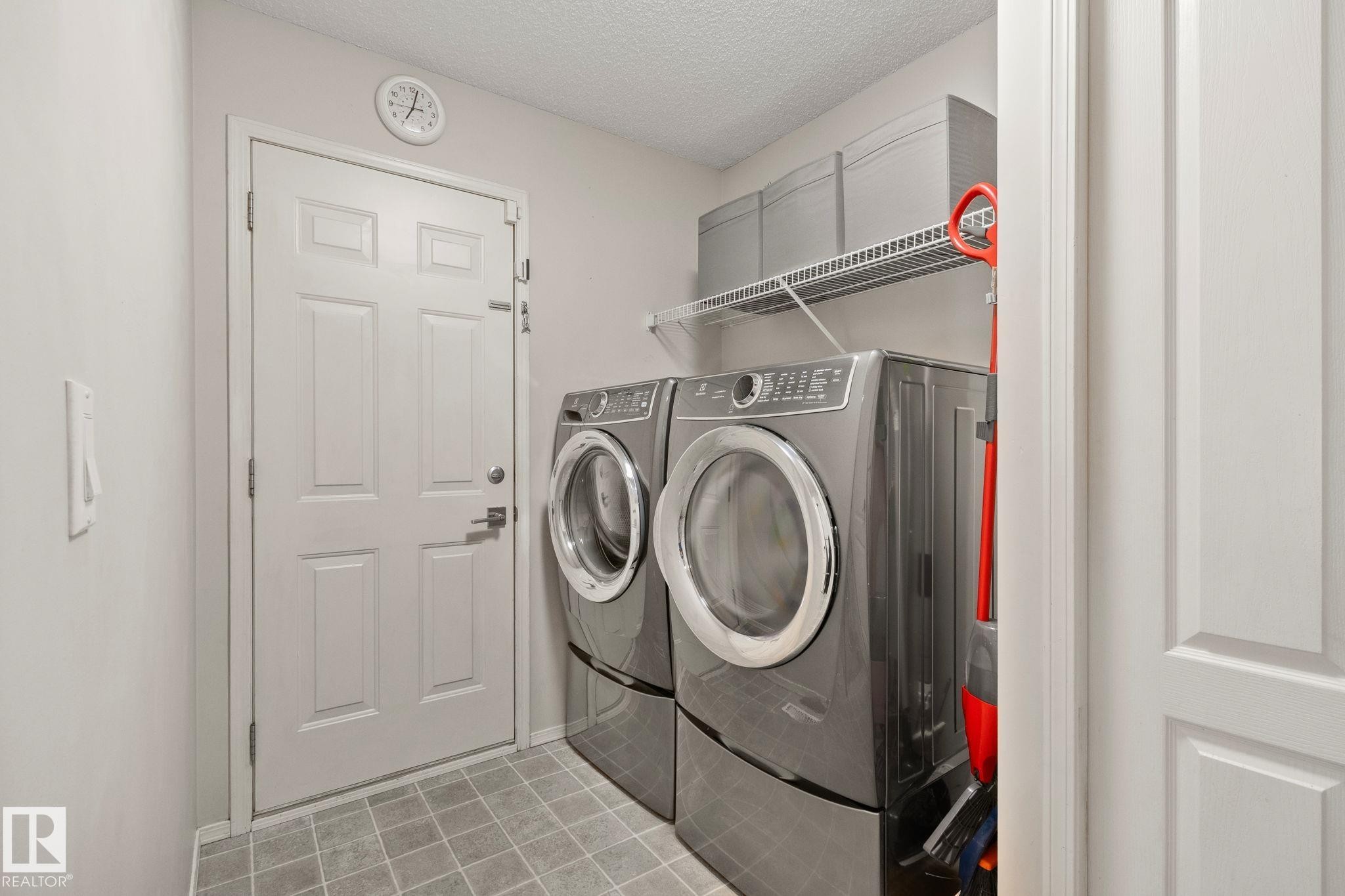 Dedicated utility area featuring tile flooring, a wire shelving system, and a paneled door - 591 Byrne Crescent Sw, Edmonton, AB - Indoor Photo Showing Laundry Room