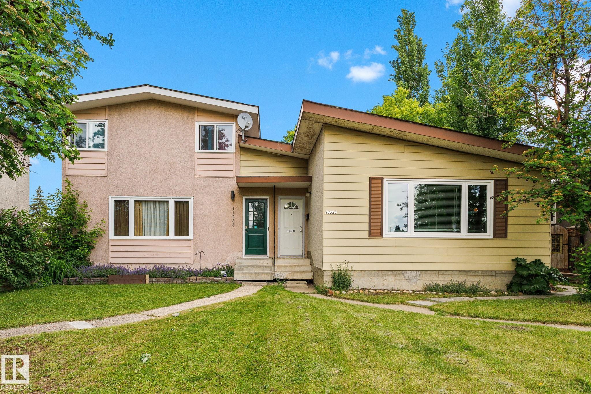 Duplex exterior with a pale pink stucco facade and a contrasting yellow siding section - 11234 40 Avenue Nw, Edmonton, AB - Outdoor