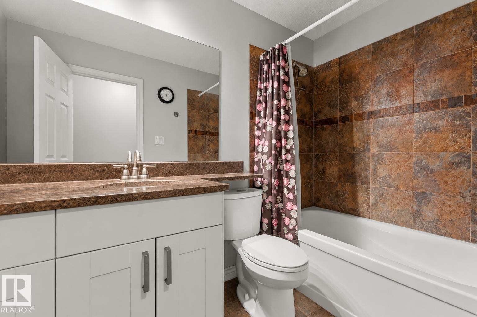 Bathroom featuring a white vanity with slab cabinet doors, brushed nickel hardware, and a stone-look countertop with an undermount sink - 11234 40 Avenue Nw, Edmonton, AB - Indoor Photo Showing Bathroom