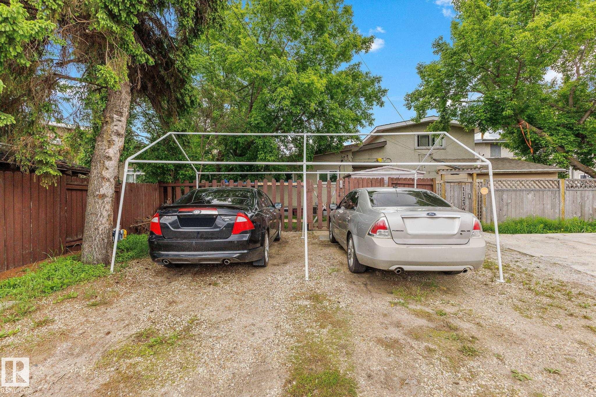 Gravel driveway featuring a two-car carport frame and mature perimeter trees - 11234 40 Avenue Nw, Edmonton, AB - Outdoor