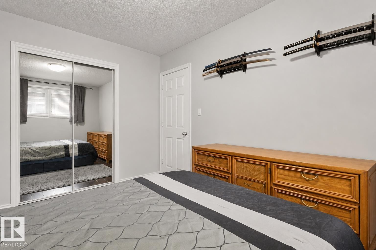 Bedroom featuring light gray walls, dark wood-finish flooring, and a mirrored closet - 11234 40 Avenue Nw, Edmonton, AB - Indoor Photo Showing Bedroom